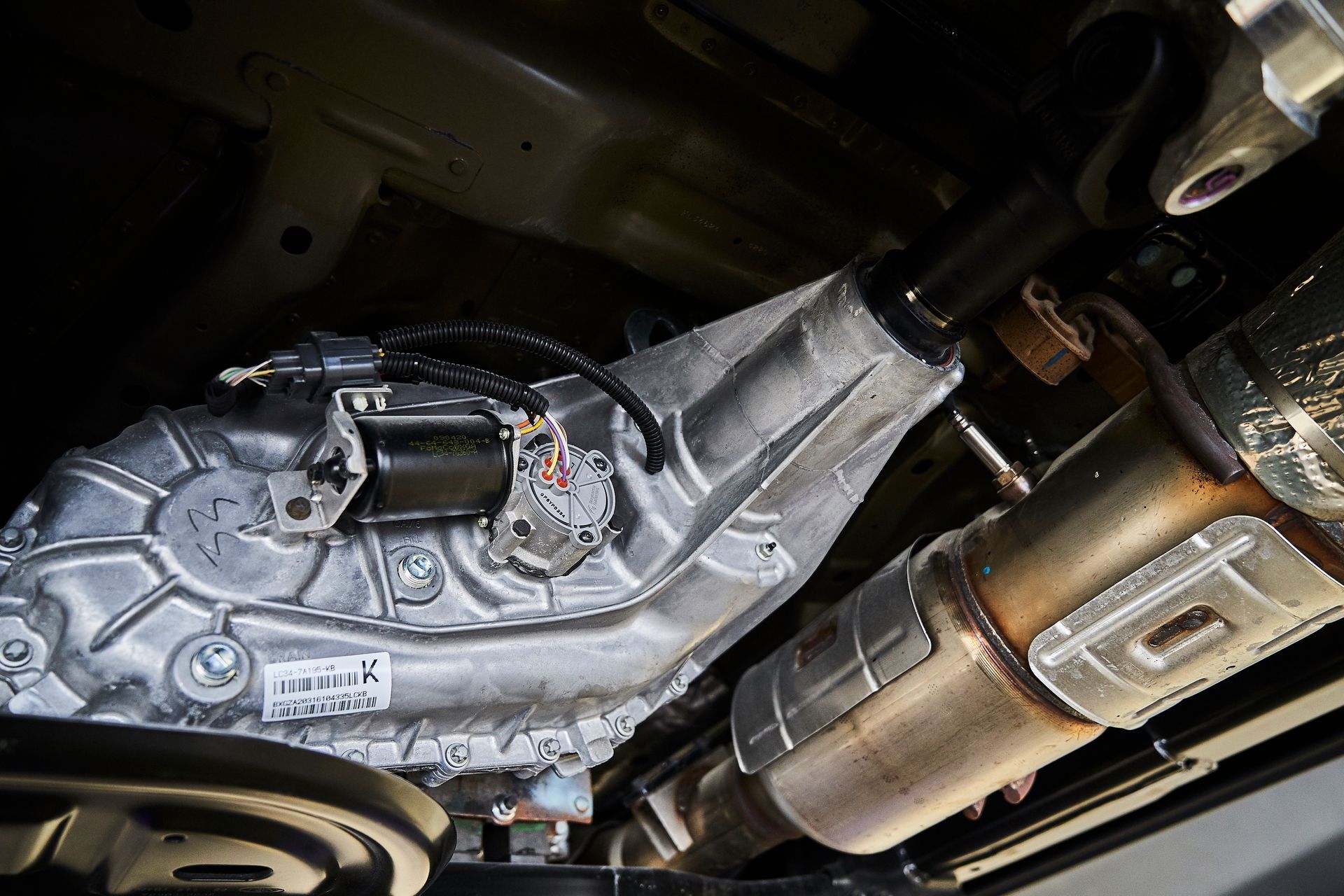 A close up of the underside of a car with a transmission and exhaust pipe.