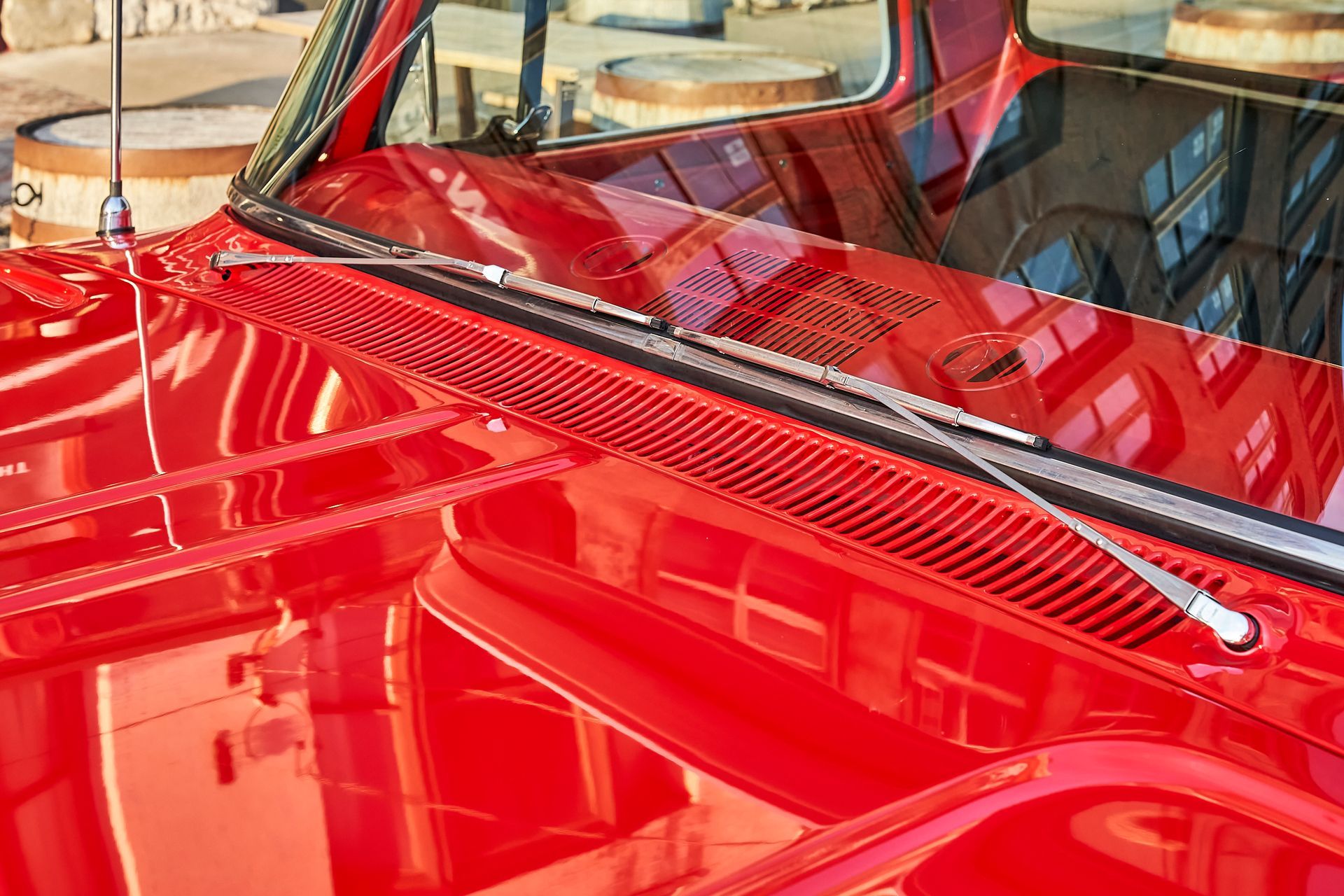 A close up of the hood of a red car with a windshield wiper.