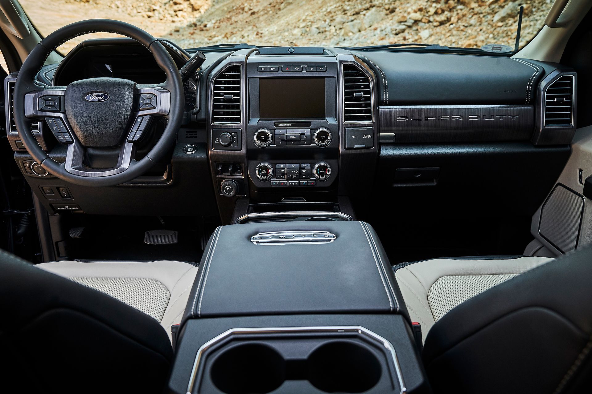 The interior of a ford f250 super duty truck with a steering wheel and a center console.