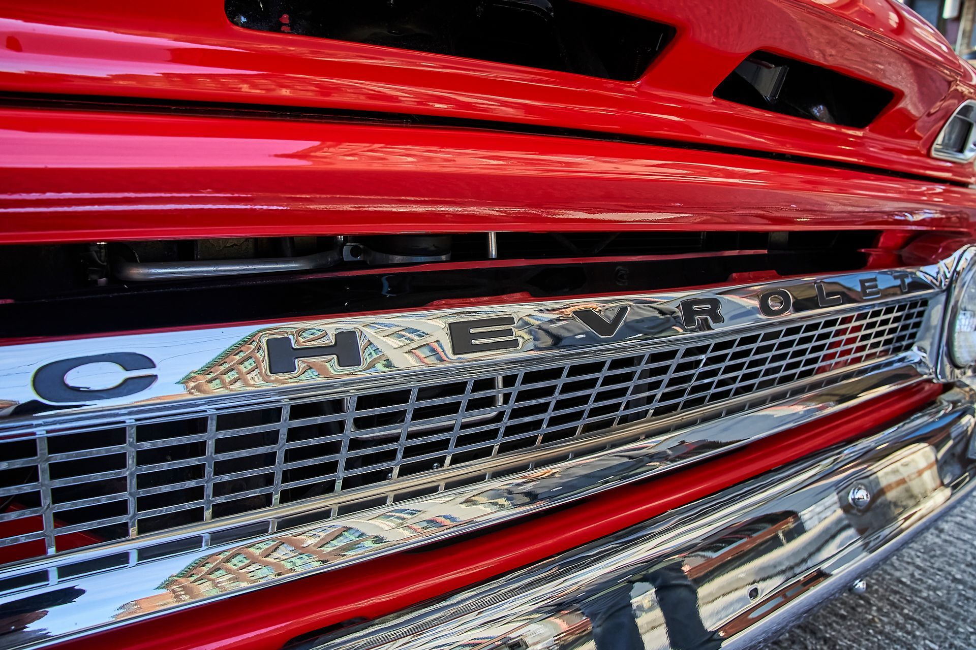 A close up of a red chevrolet truck 's grille