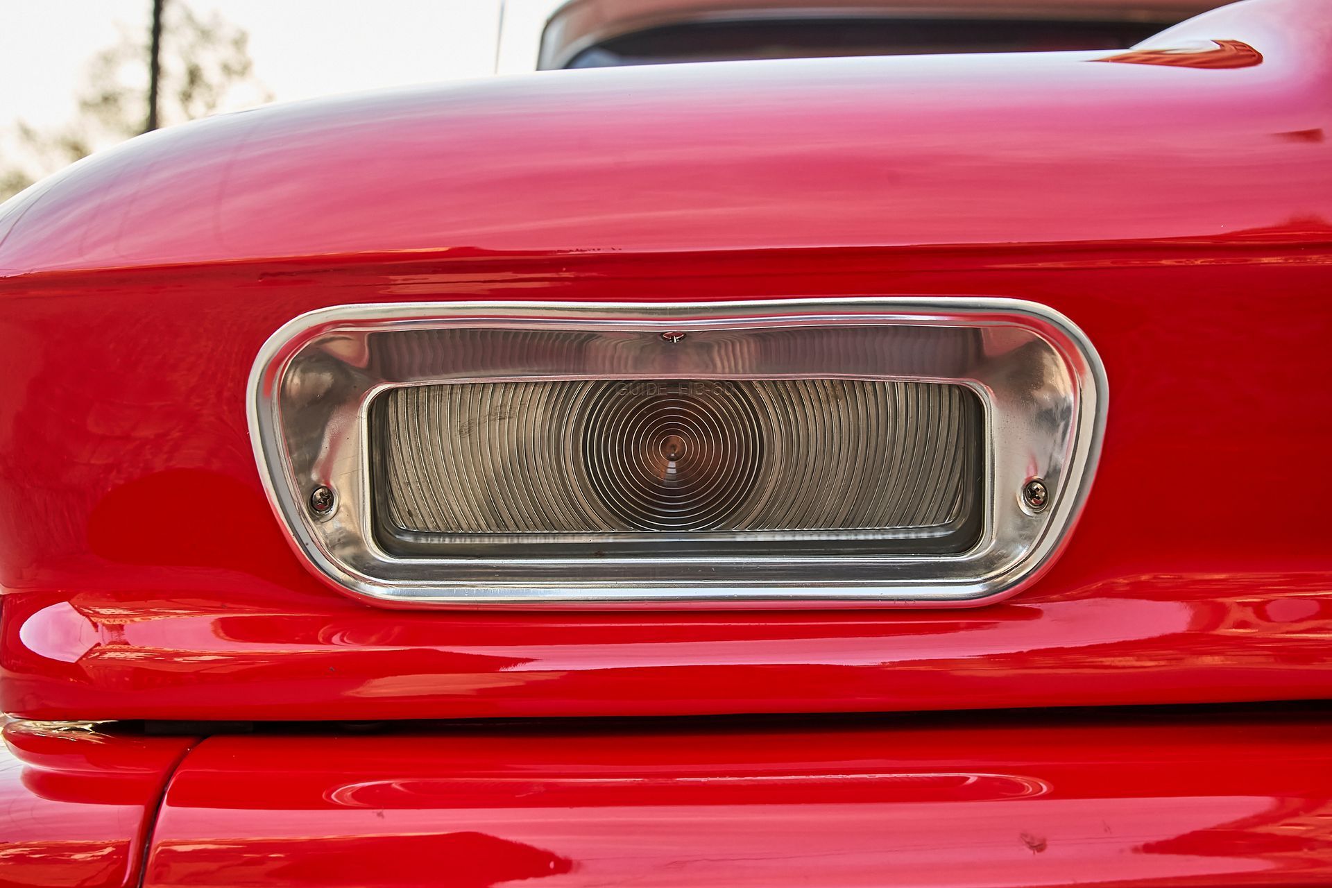 A close up of a red car 's license plate light.