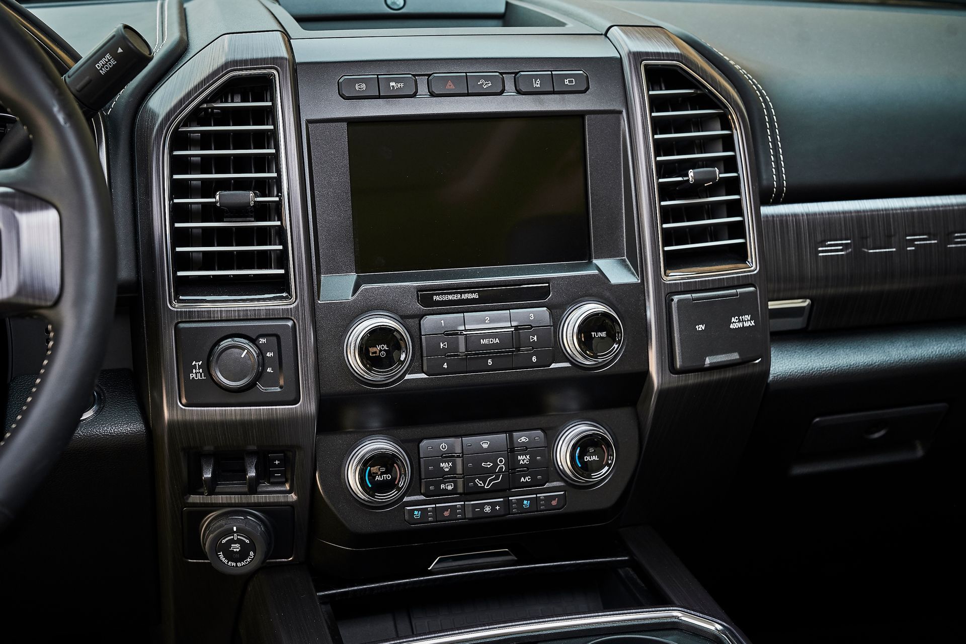 A close up of a car dashboard with a radio and a steering wheel.