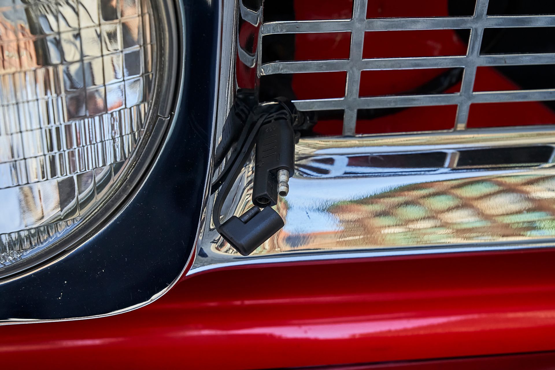 A close up of a red car 's headlight and grille.