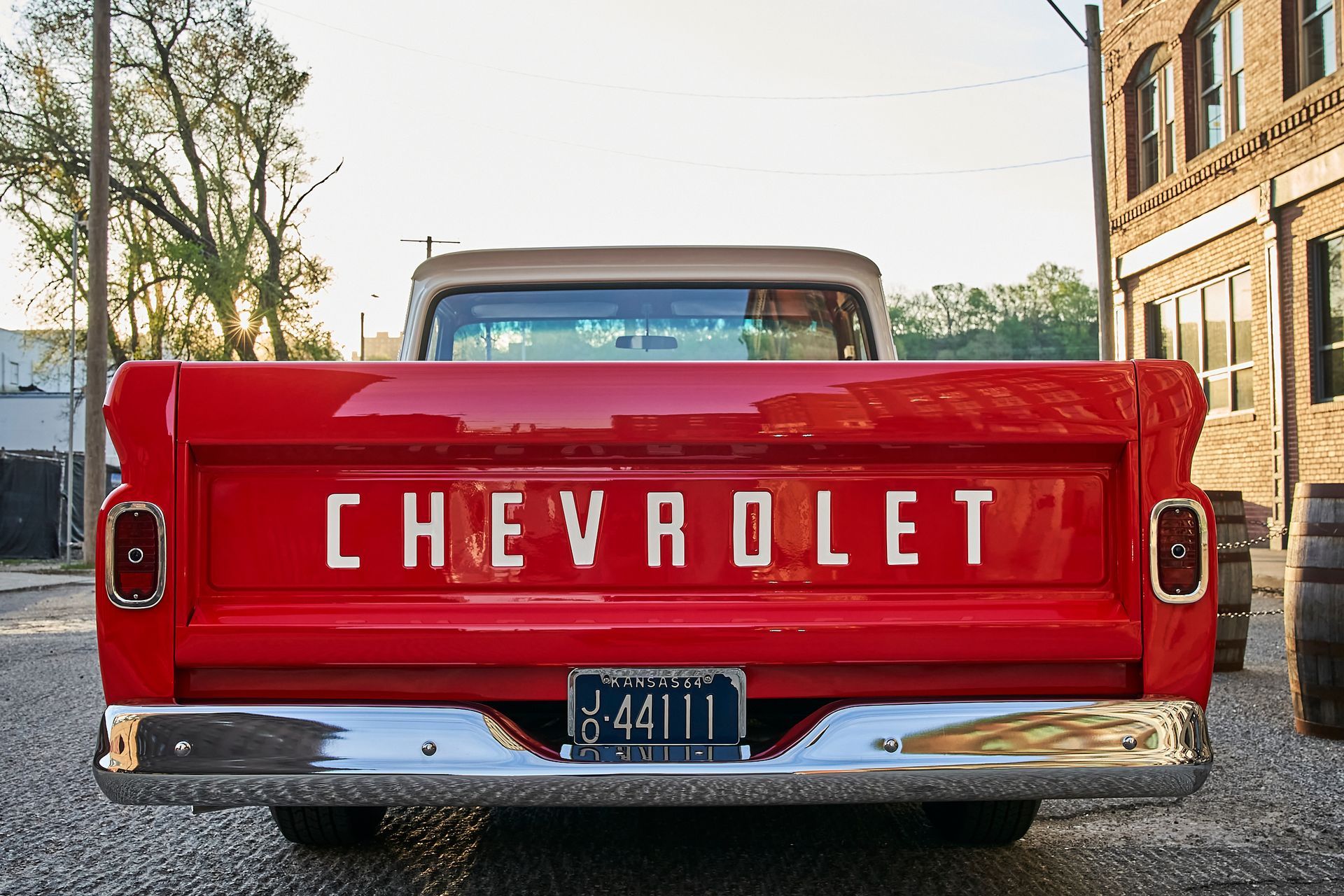 A red chevrolet truck is parked in front of a building.