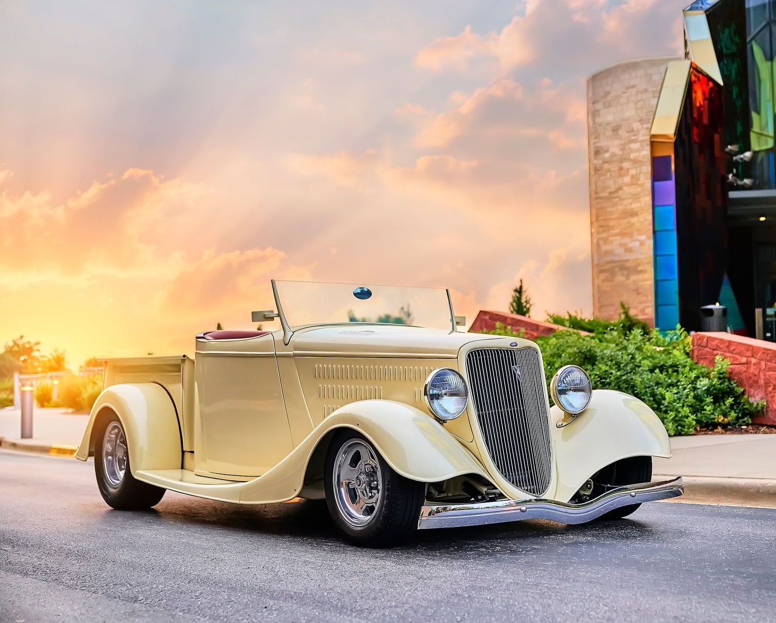 A yellow car is parked on the side of the road in front of a building.