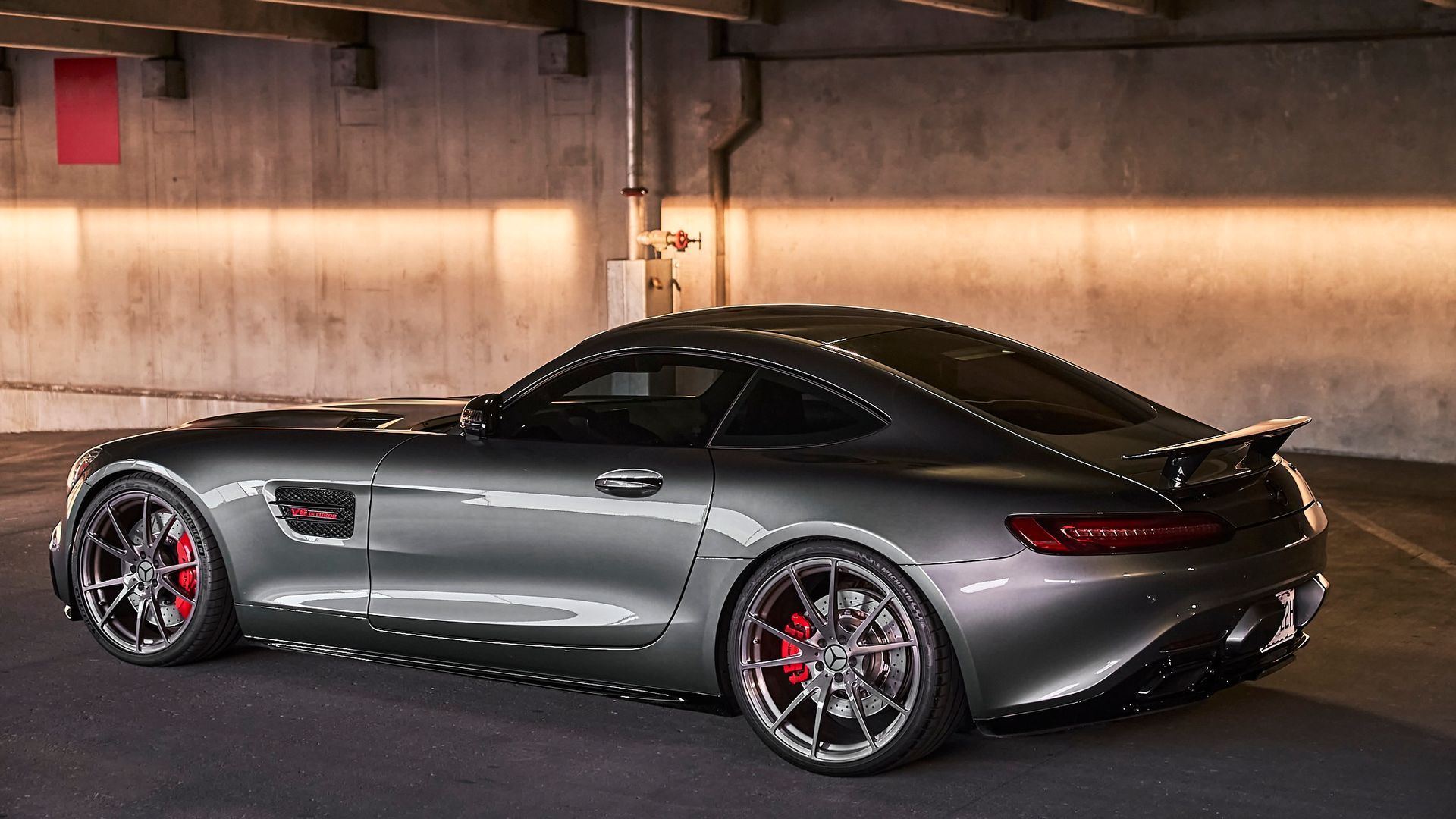 A gray sports car is parked in a parking garage.