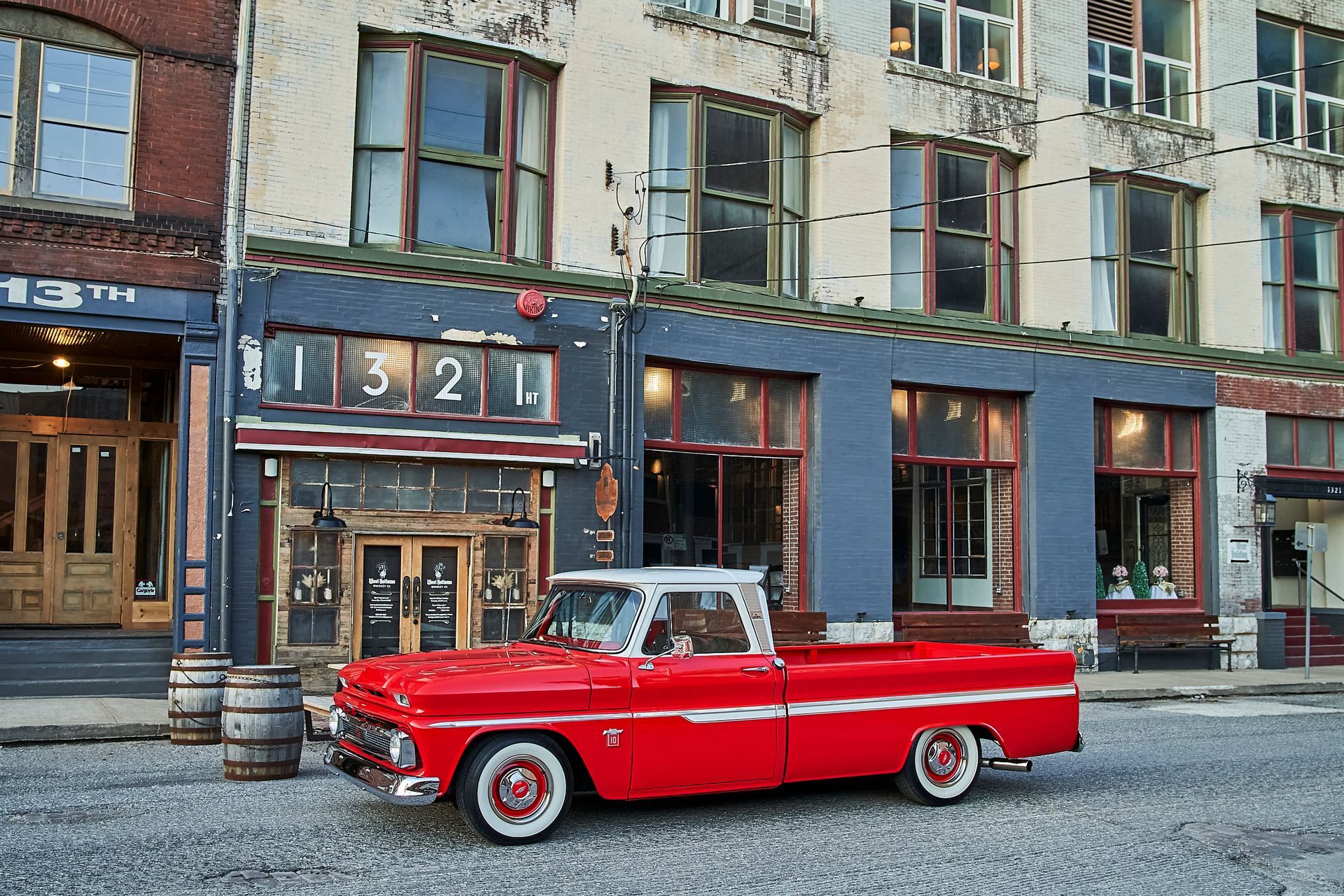 A red pickup truck is parked in front of a building with the number 1324 on it