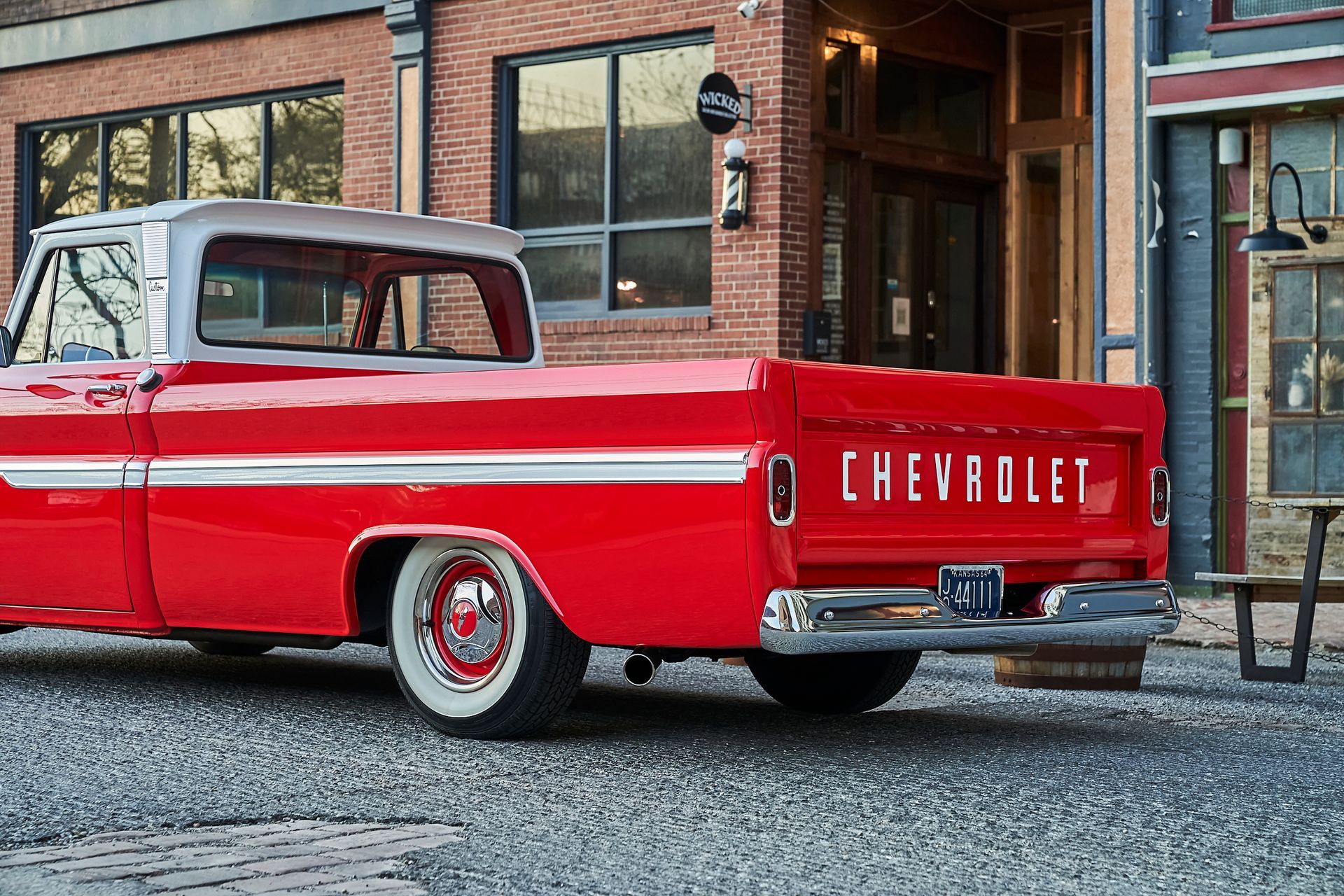 A red chevrolet truck is parked in front of a brick building.