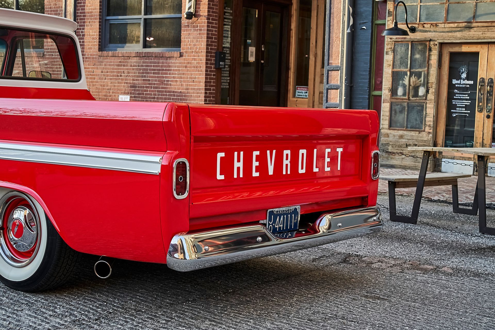 A red chevrolet truck is parked in front of a building
