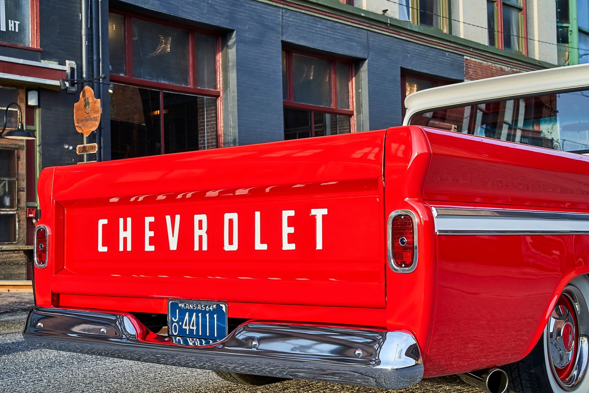 A red chevrolet truck is parked in front of a building