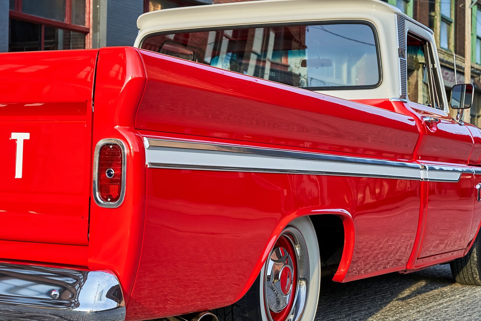 A red truck with the letter t on the back is parked in front of a building