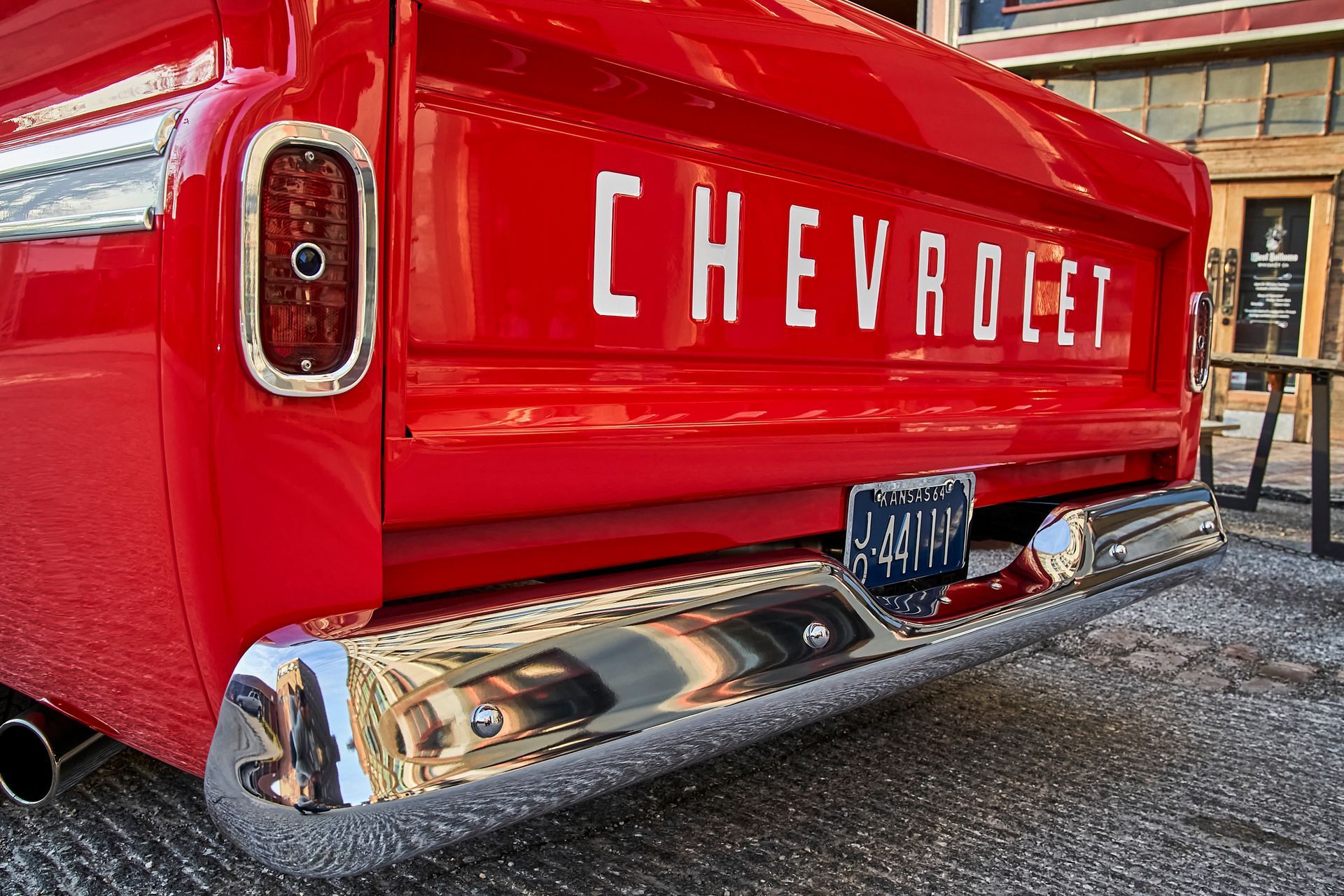 A red chevrolet truck is parked in front of a building