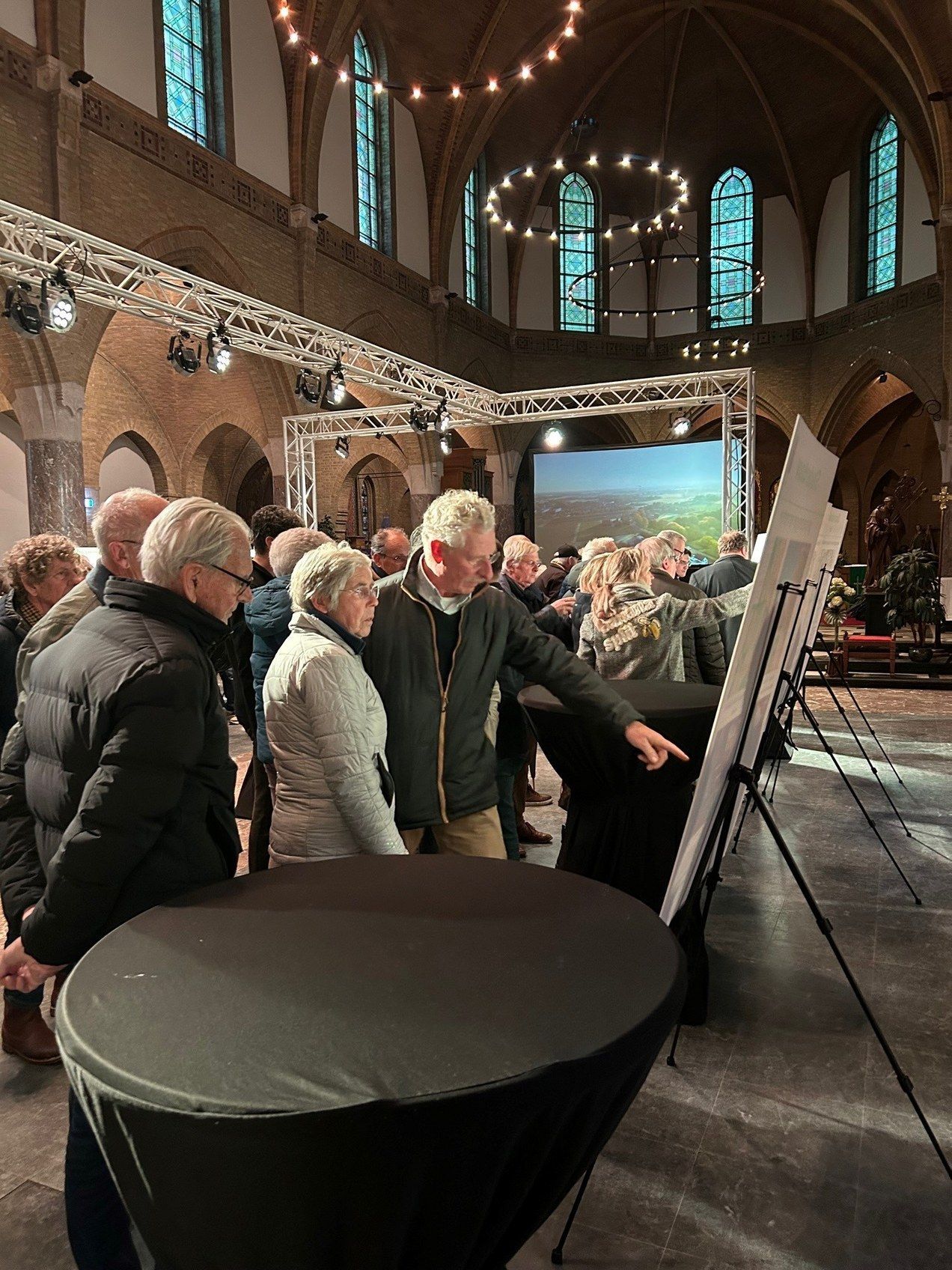 Een groep mensen staat rond een tafel in een kerk en bekijkt een kaart.