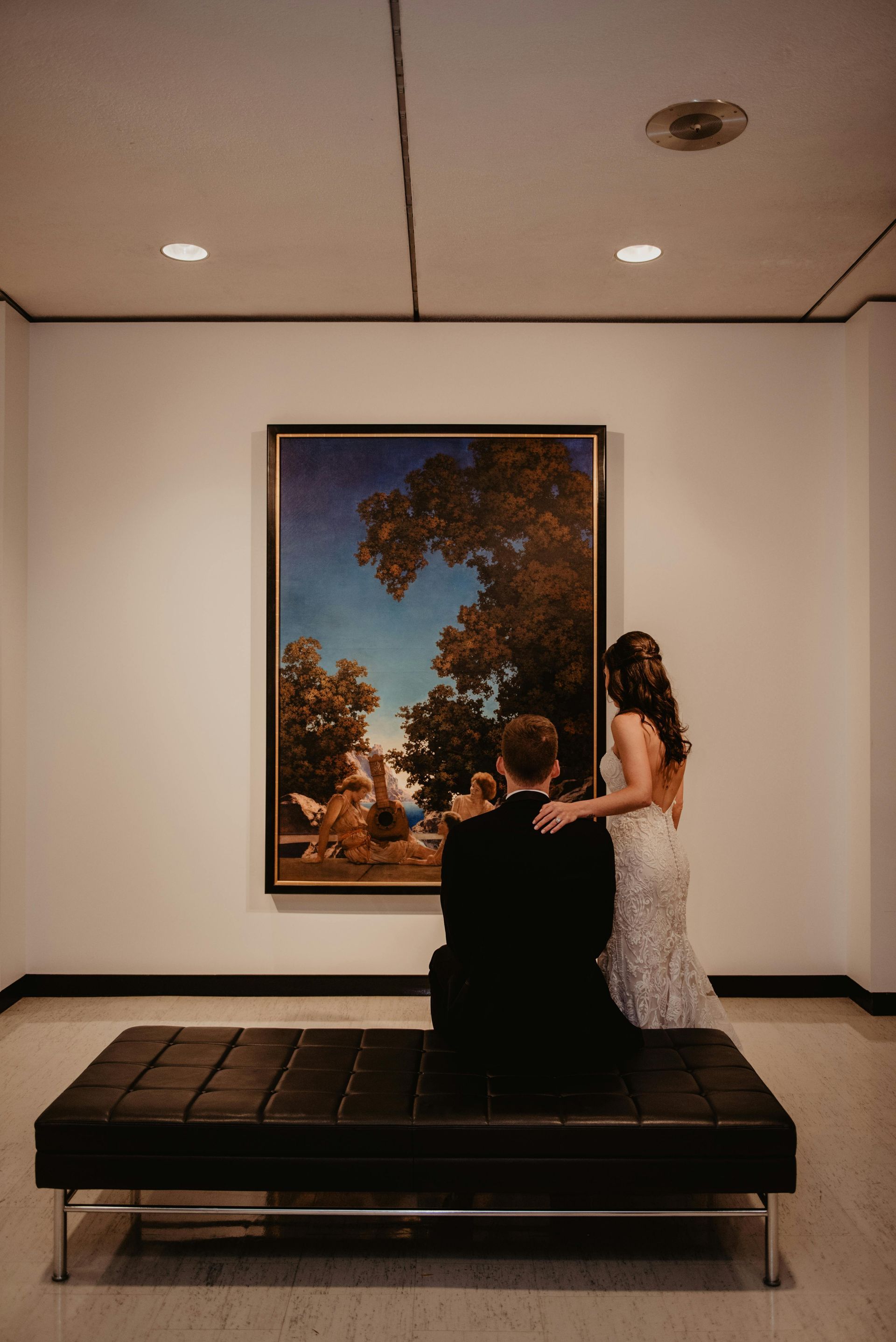 A woman is standing in a hallway looking at her cell phone.