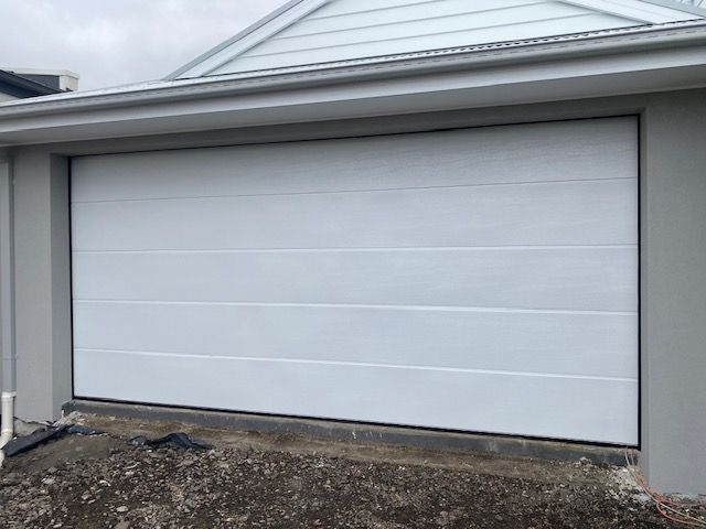 White garage door on a house exterior above a gravel driveway