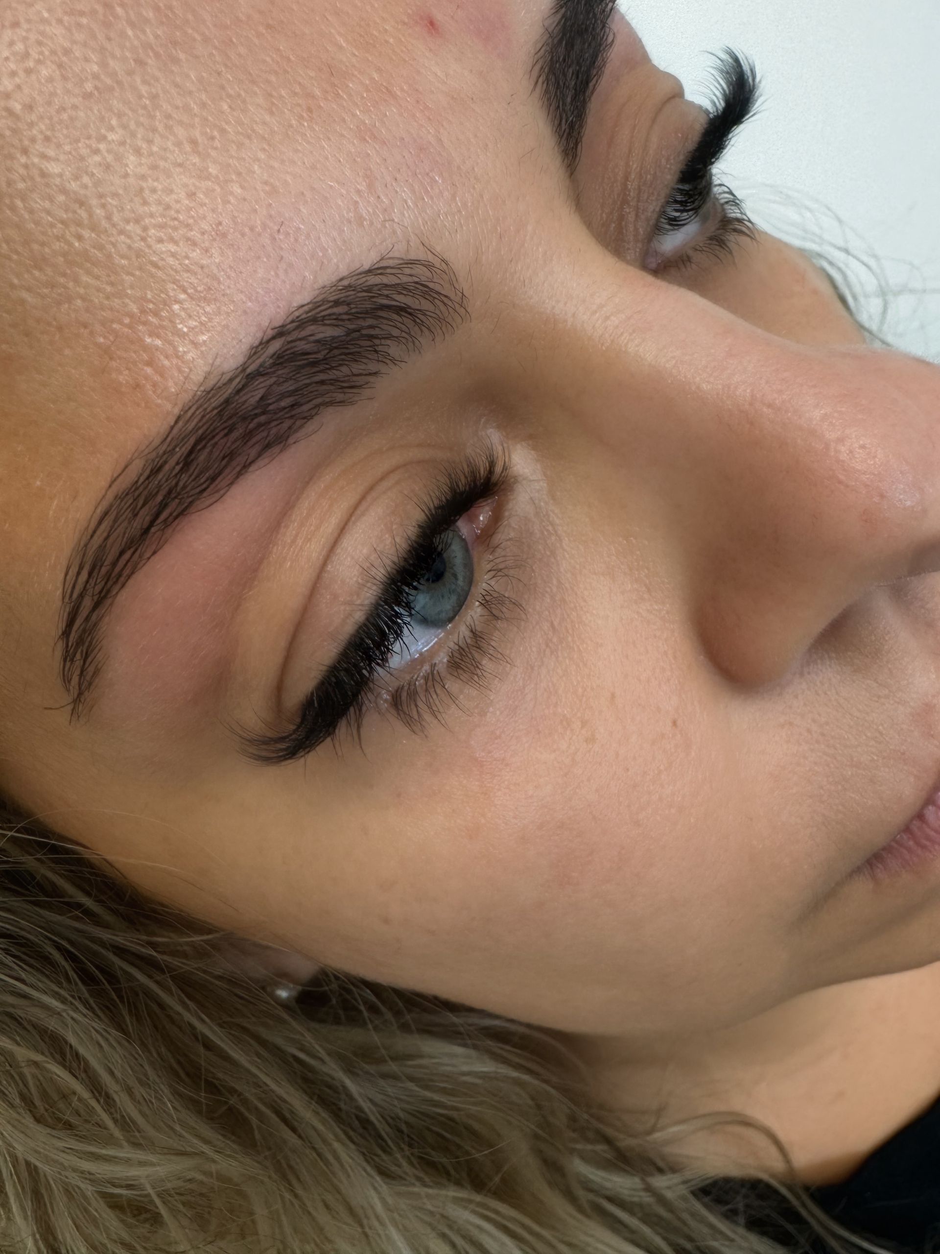 Woman's face with dark, well-defined eyebrows and eyeliner, blue eyes.