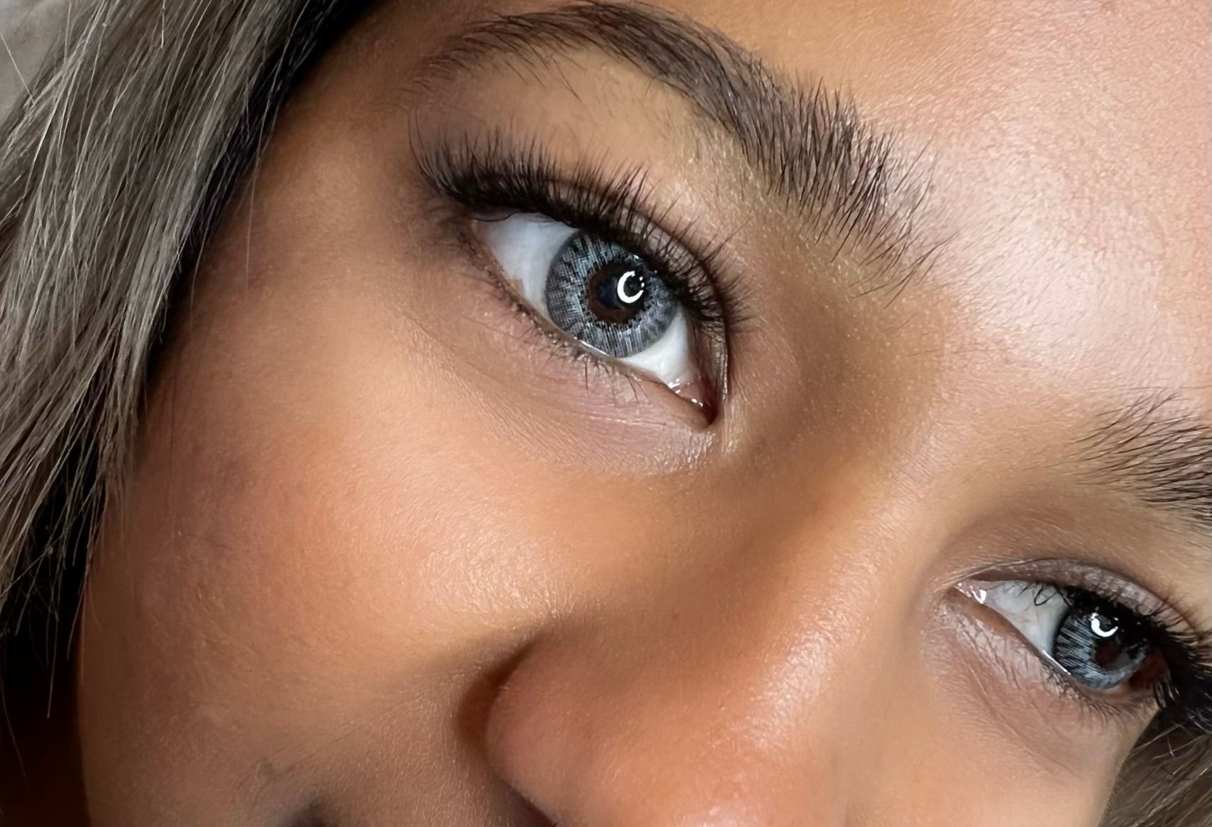 Close-up of a person's eyes, light gray irises with long dark eyelashes.