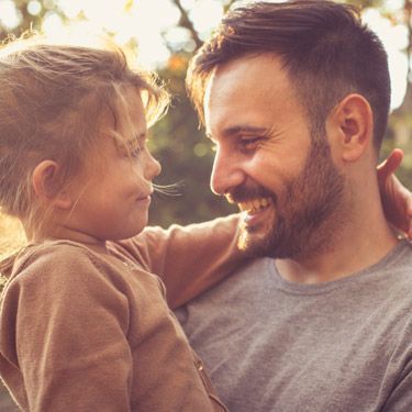 A man is holding a little girl in his arms.