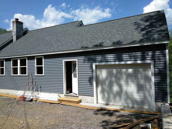 A gray house with a white garage door and a porch.