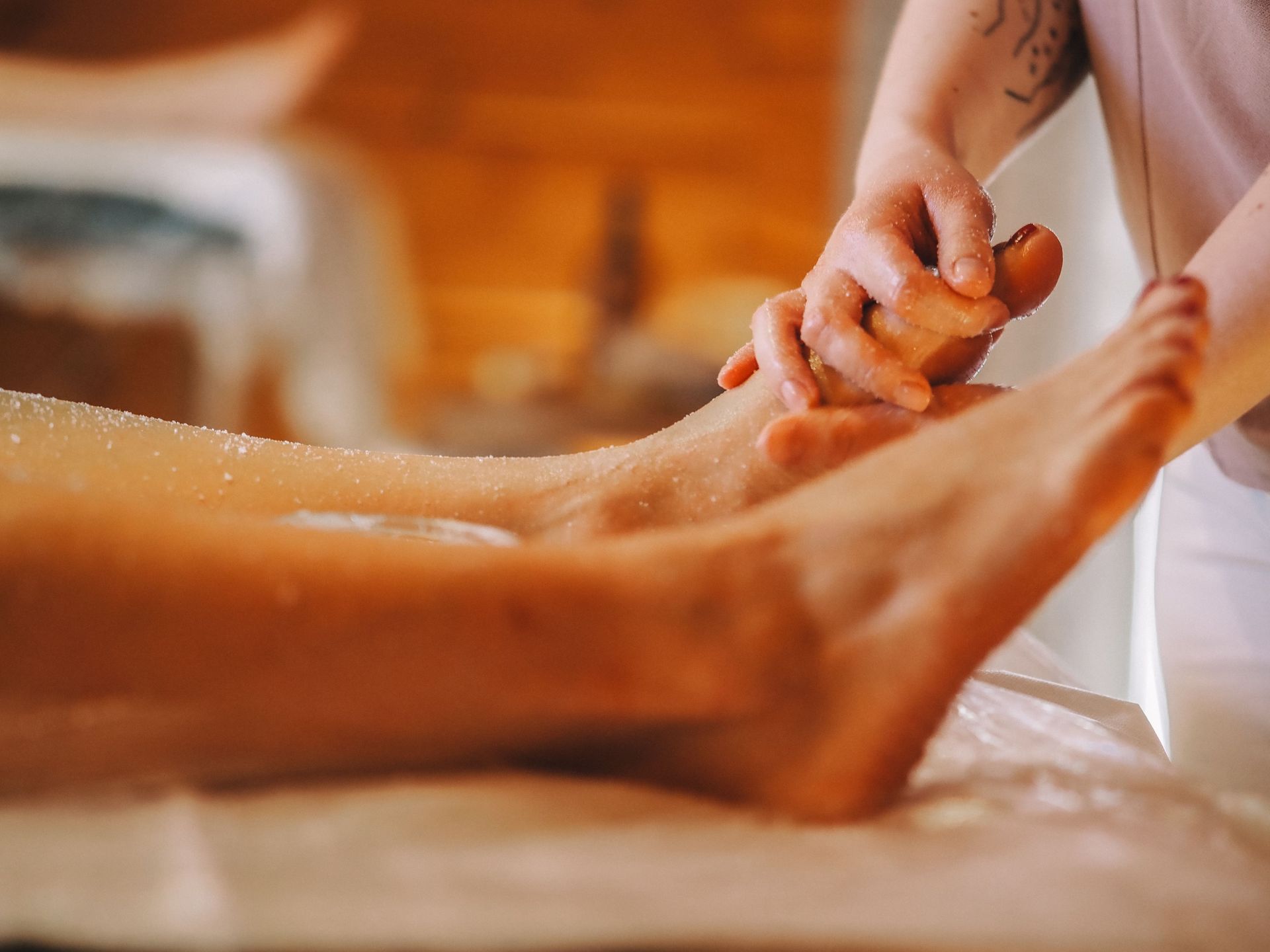 Foot massage on a person’s leg and foot with oil in a warm spa setting