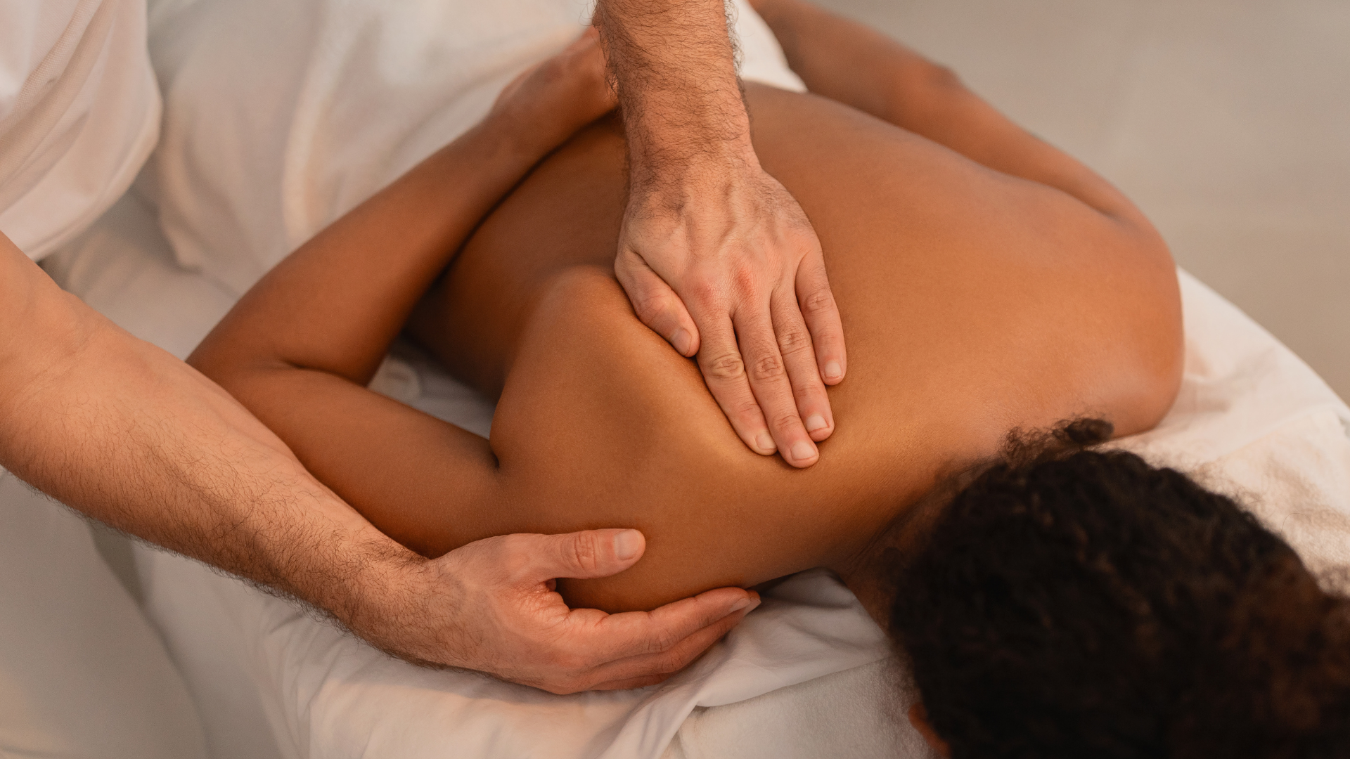 Hands massaging a person's neck and shoulders during a deep tissue session