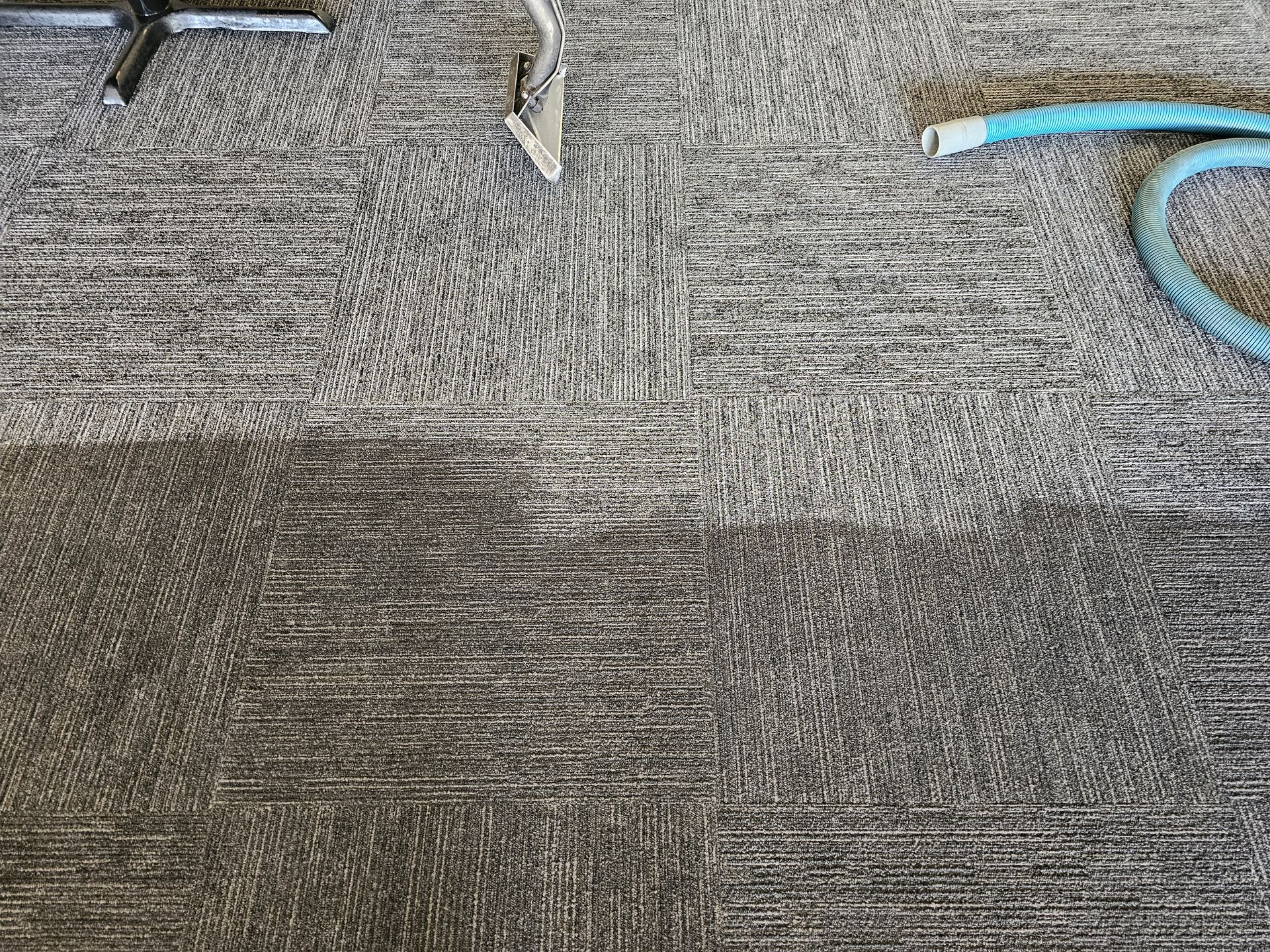 Man in overalls cleans carpet with industrial vacuum in a sunny room.