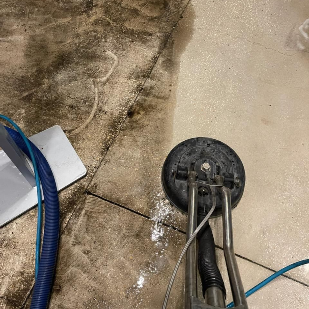 Person using a floor buffer machine in a tiled indoor area. The machine is blue and silver.