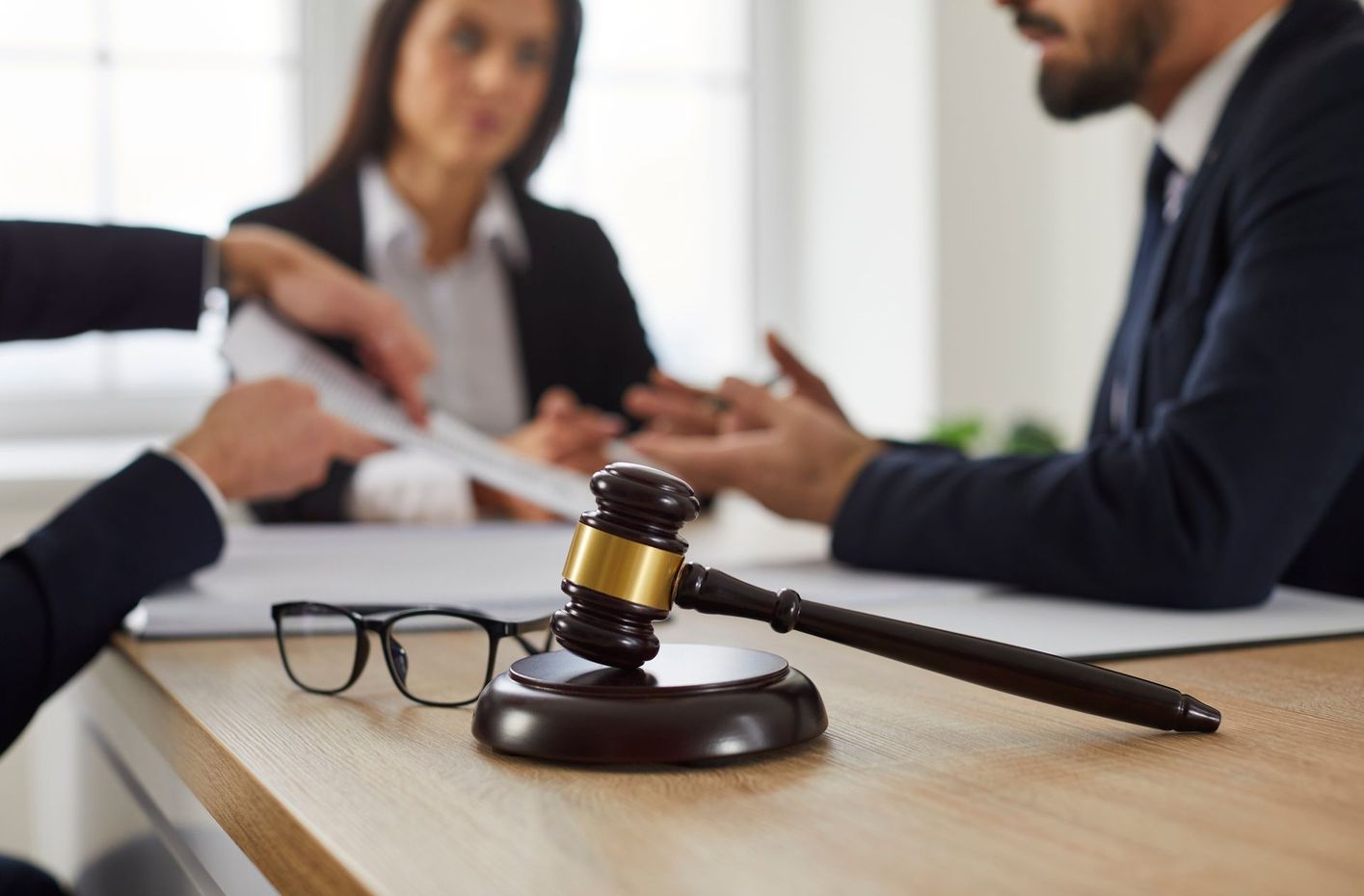 A judge's gavel is sitting on a wooden table in front of a group of people.