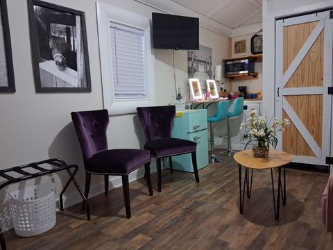 A waiting area featuring two purple velvet chairs, a small round table with flowers, and a turquoise cabinet. A waiting area featuring two purple velvet chairs, a small round table with flowers, and a turquoise cabinet.