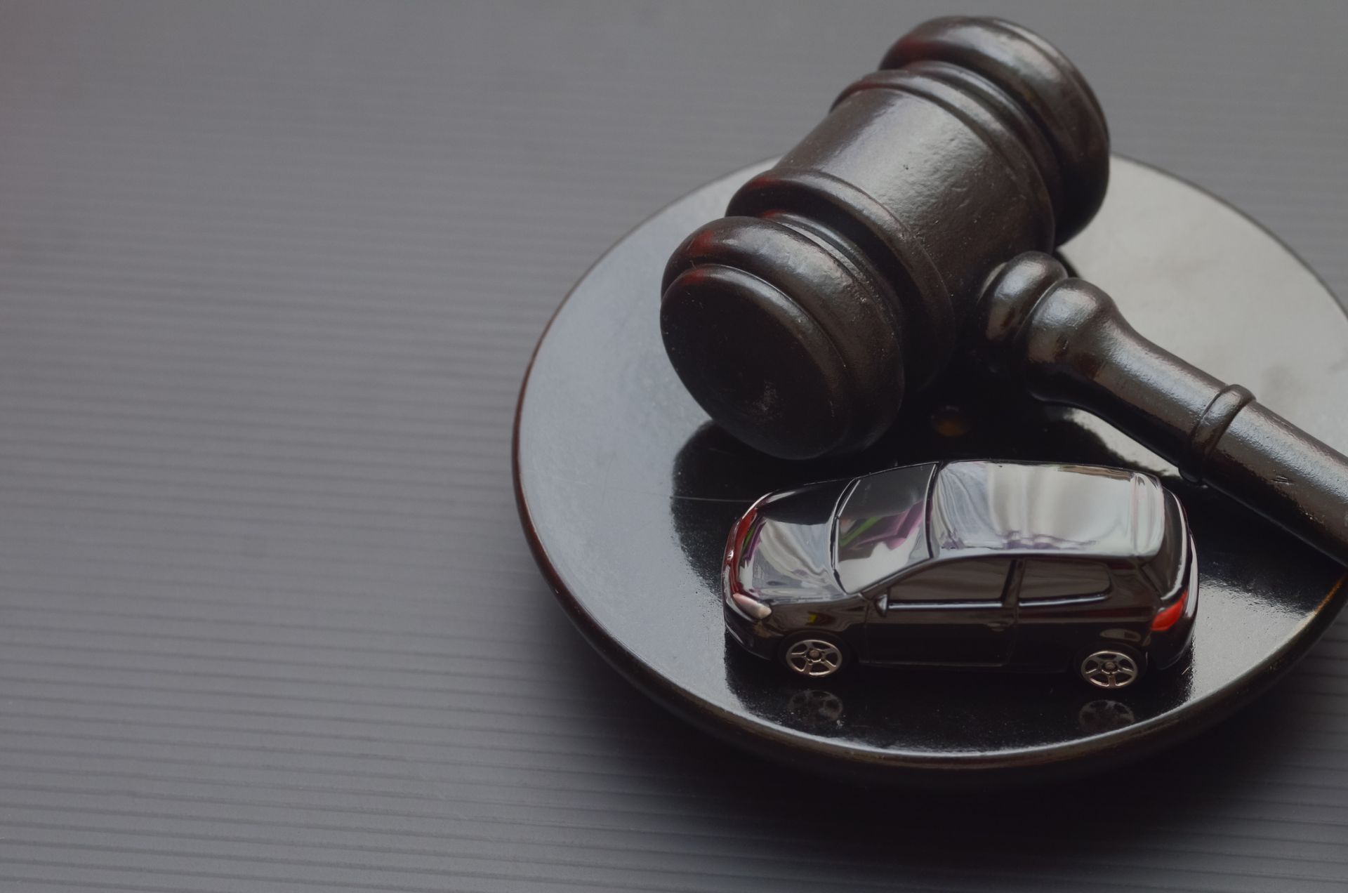 A judge's gavel and a miniature black car symbolize the intersection of law and automobiles.