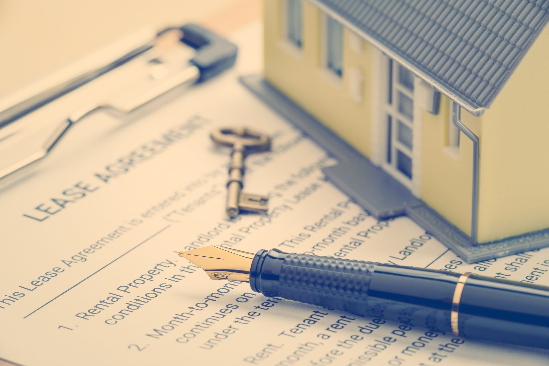 Lease agreement with model house, keys, and pen, suggesting a housing contract signing.