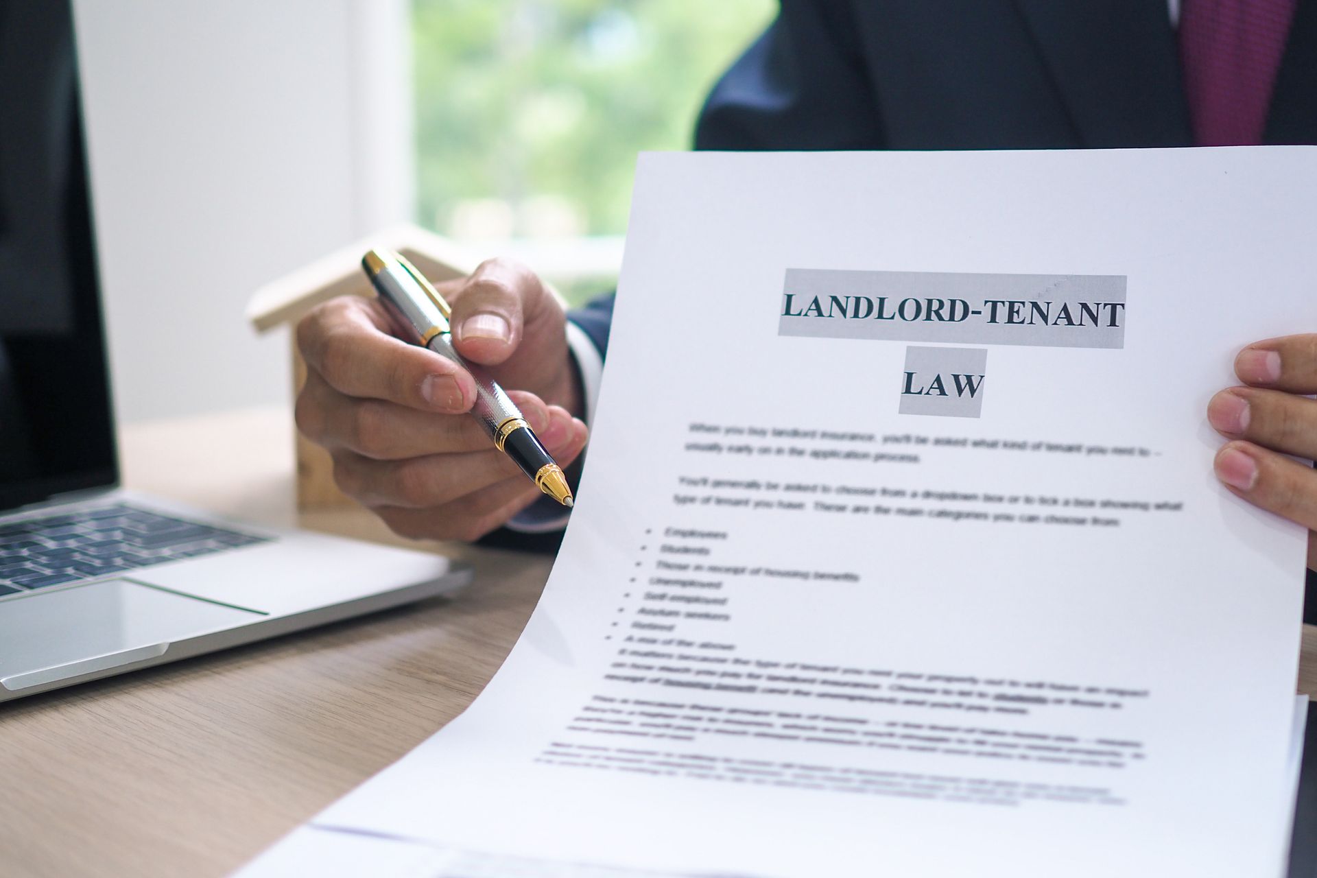 Landlord tenant lawyer reviewing house contract with pen, legal help for rental property disputes.