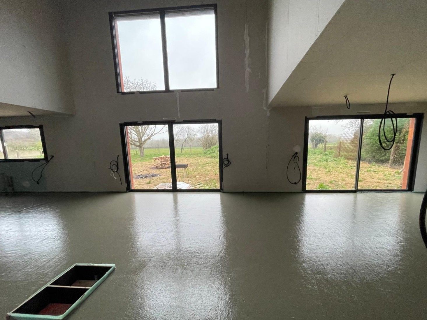 Une grande pièce vide avec beaucoup de fenêtres et un sol en béton.