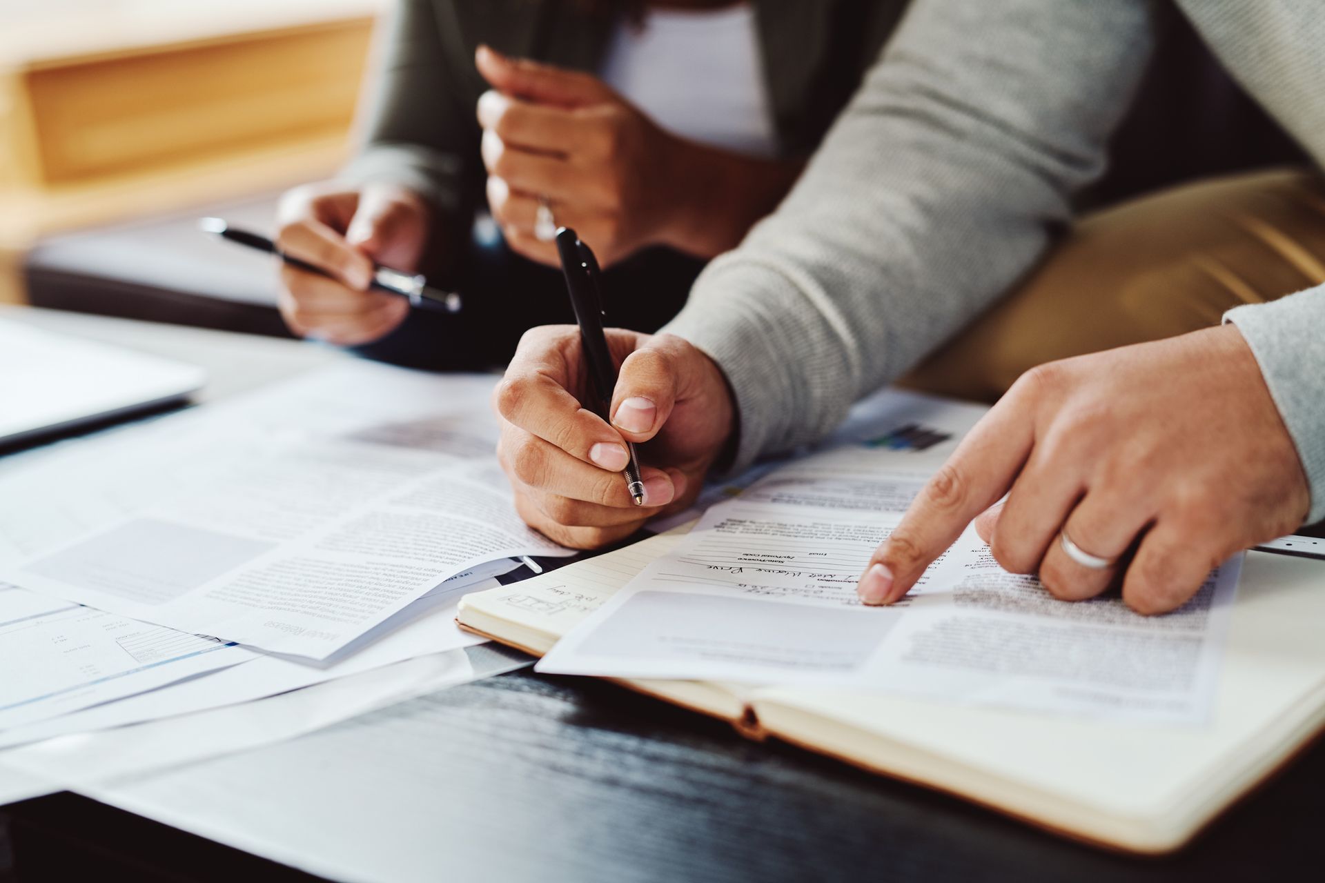 A man and a woman are sitting at a table writing in a notebook. A man and a woman are sitting at a table writing in a notebook.