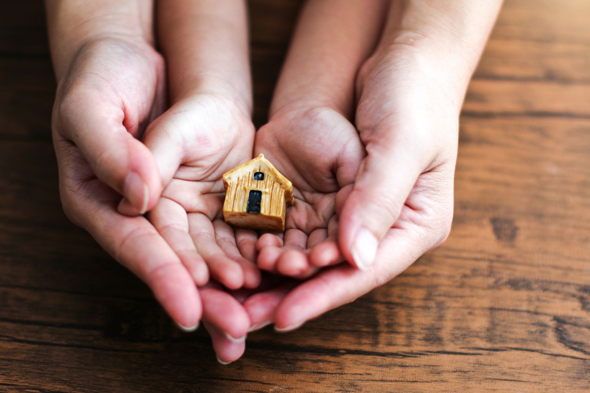 A woman and child are holding a small wooden house in their hands. A woman and child are holding a small wooden house in their hands.