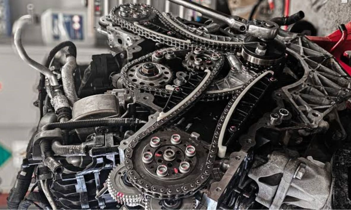 Close-up of a disassembled engine with gears, chains, and mechanical components in a workshop.