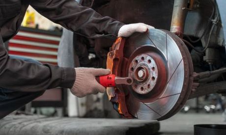 Mechanic replacing brake rotor on car. Showing the rotor, caliper, and wrench.