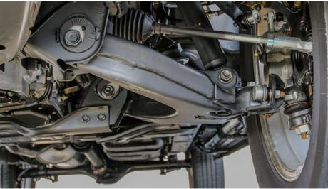 Undercarriage of a vehicle, showing suspension components: control arms, shock absorber, and steering linkage.