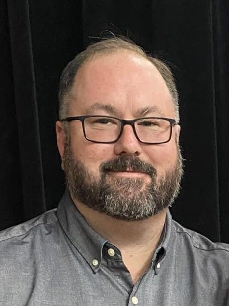 A man wearing glasses and a gray
shirt.