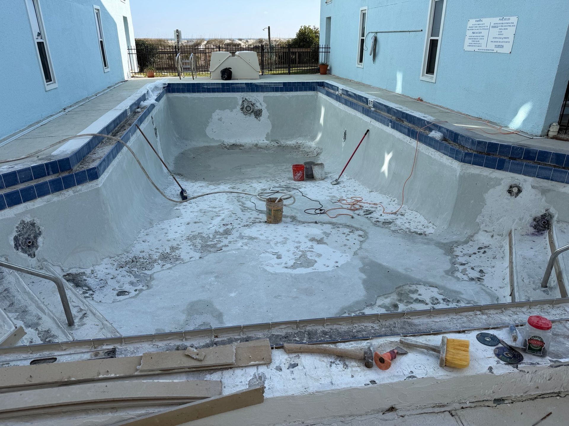 Empty swimming pool under construction, light blue walls, gray concrete.