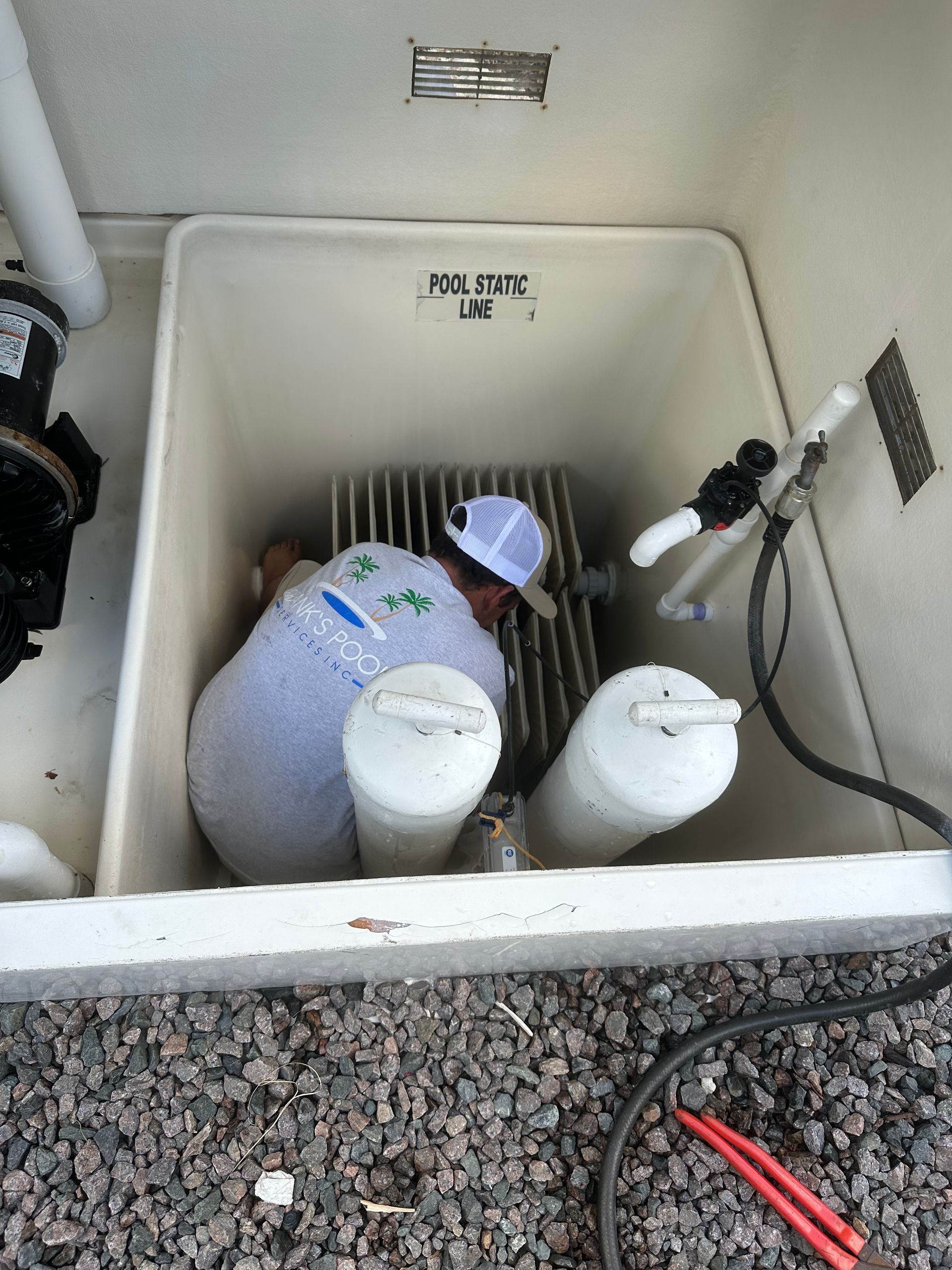 A person inside a white basin is working on pool equipment.
