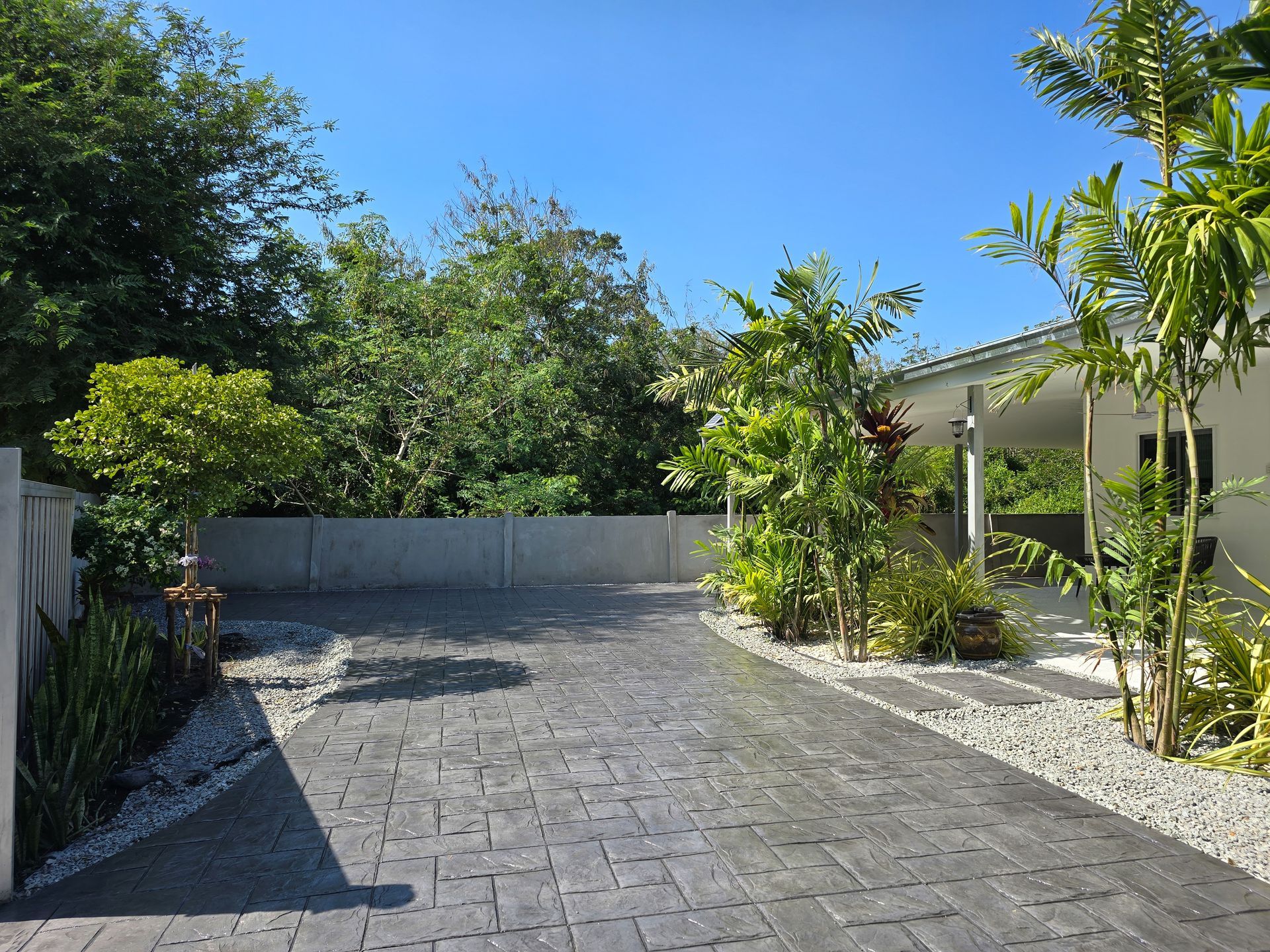 Pool with clear, turquoise water. Palm fronds cast shadows. White pool steps.