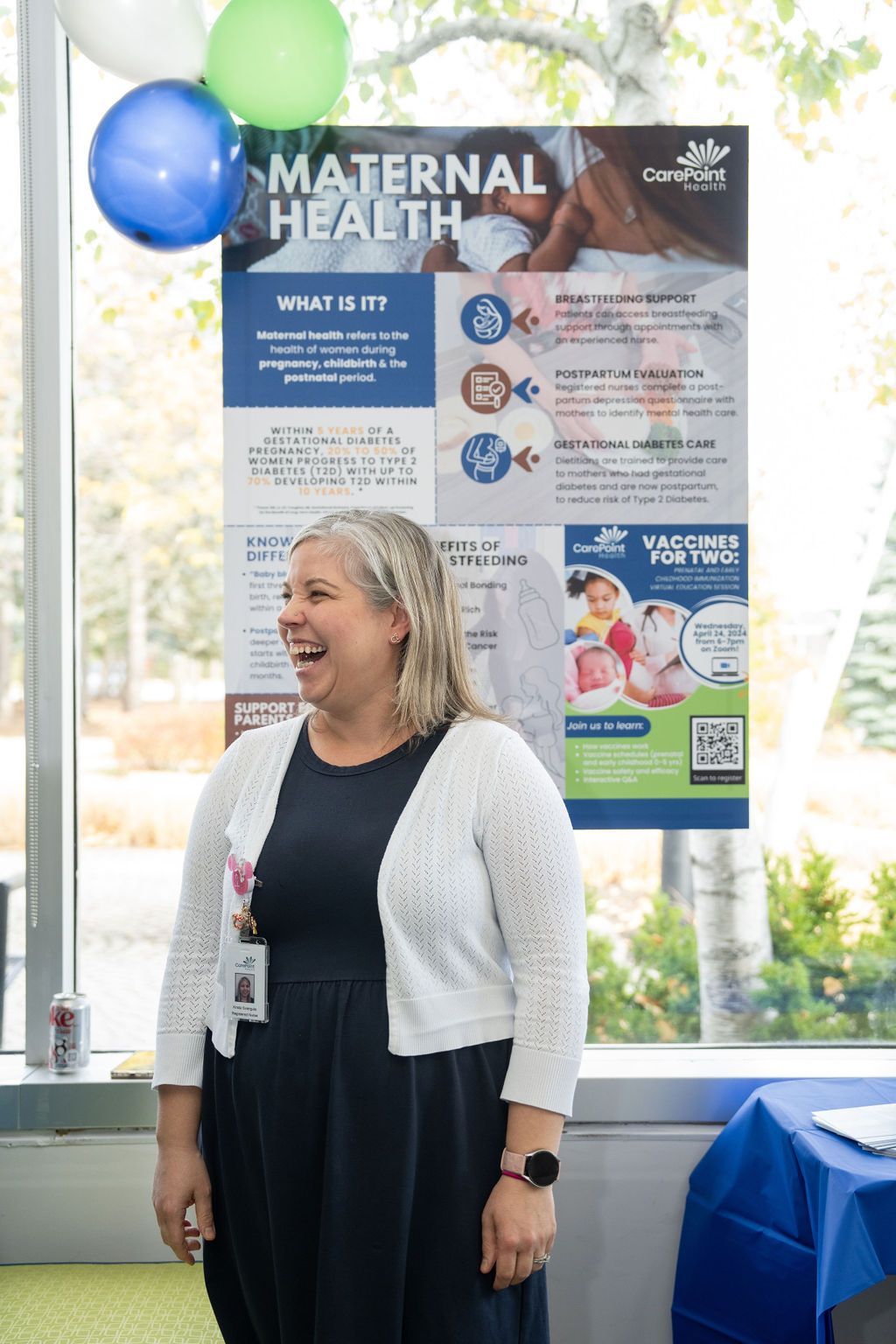 A woman is standing in front of a poster about maternal health.