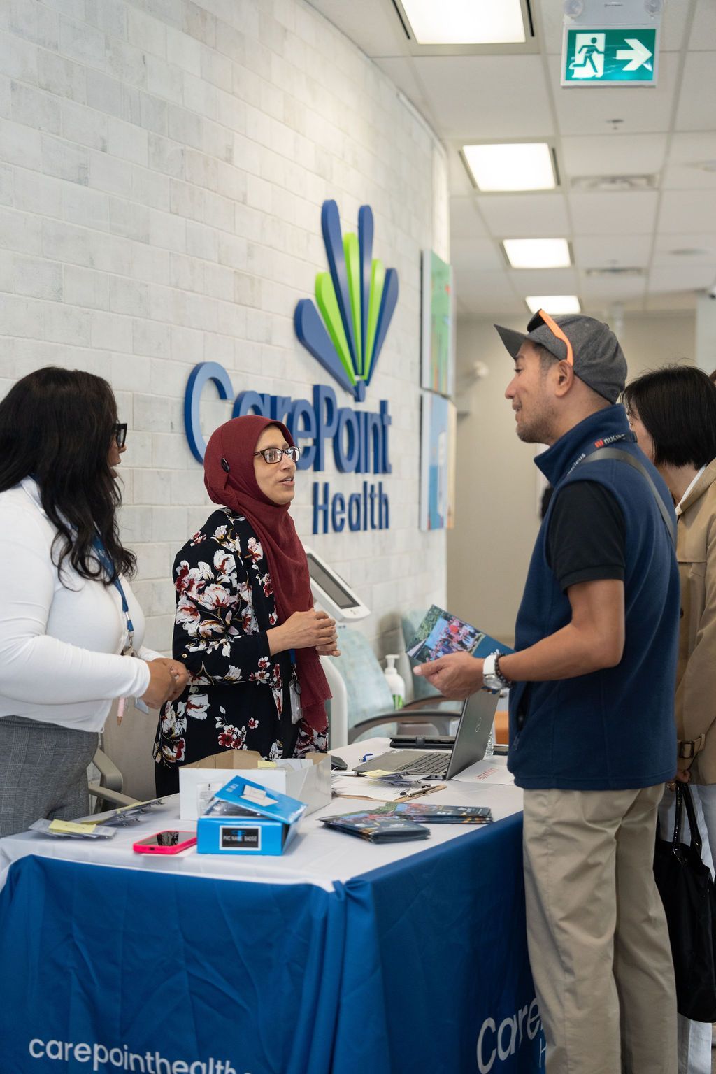 A group of people are standing around a table in front of a sign that says careport health.