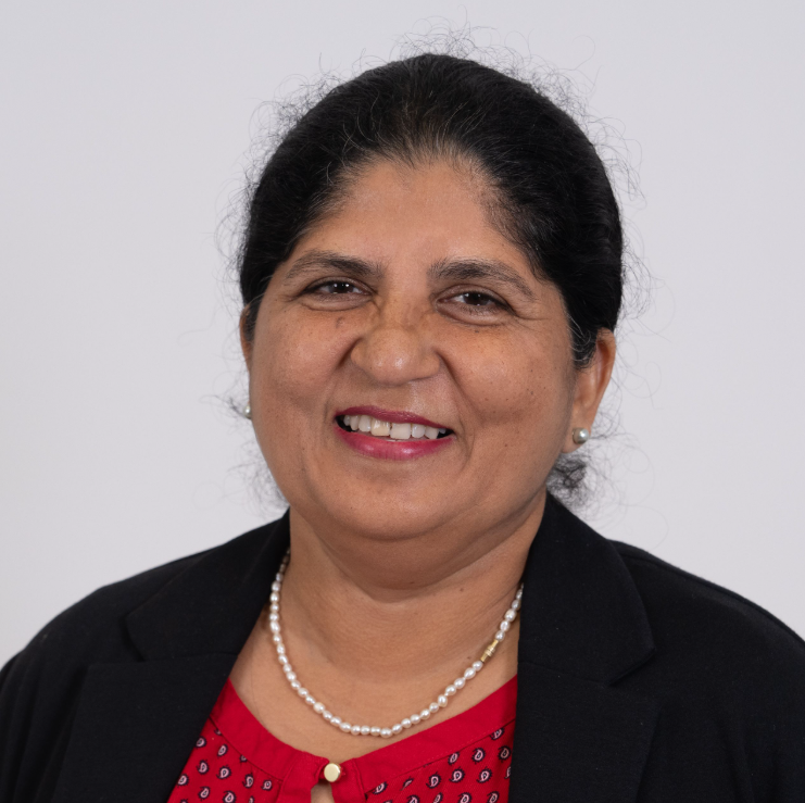 A woman wearing a red shirt and a black jacket is smiling for the camera.
