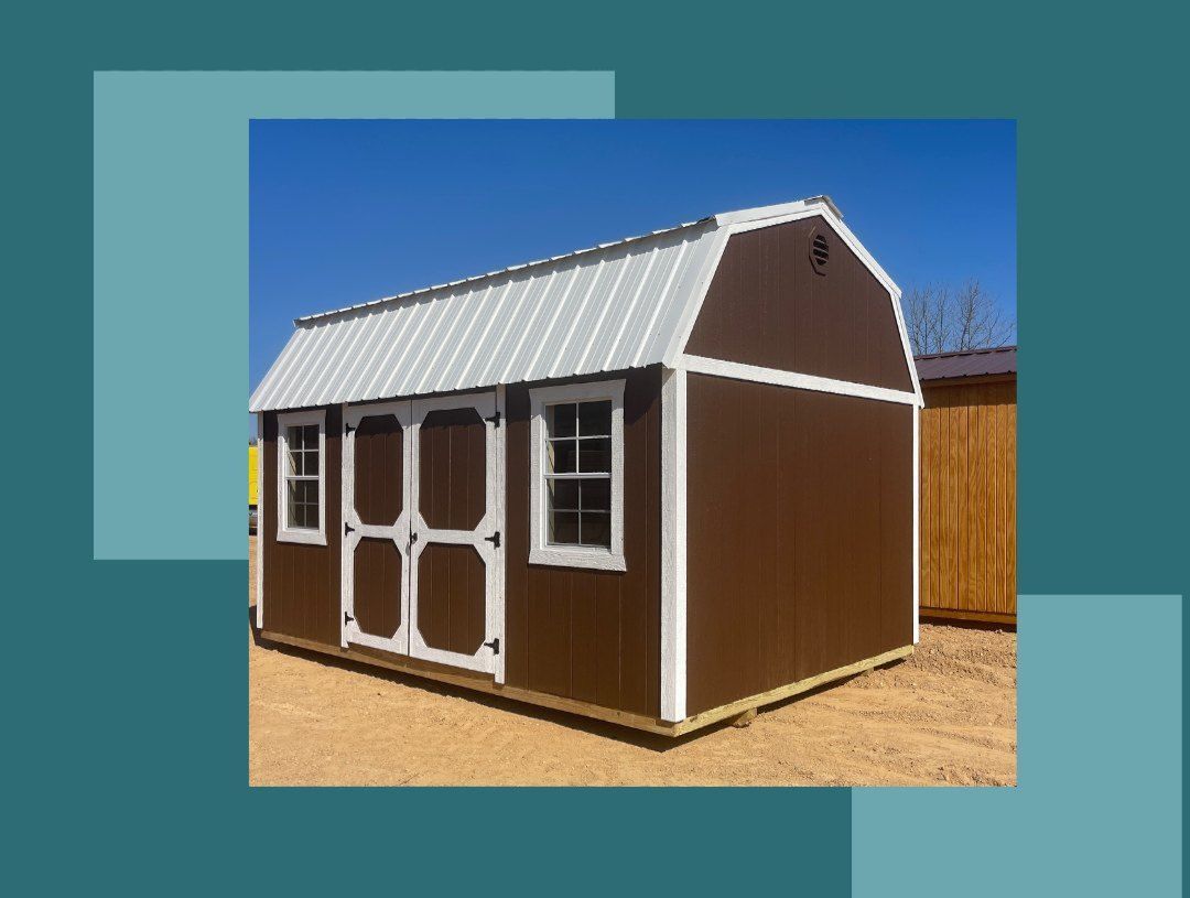 A gray barn with a black roof and a door