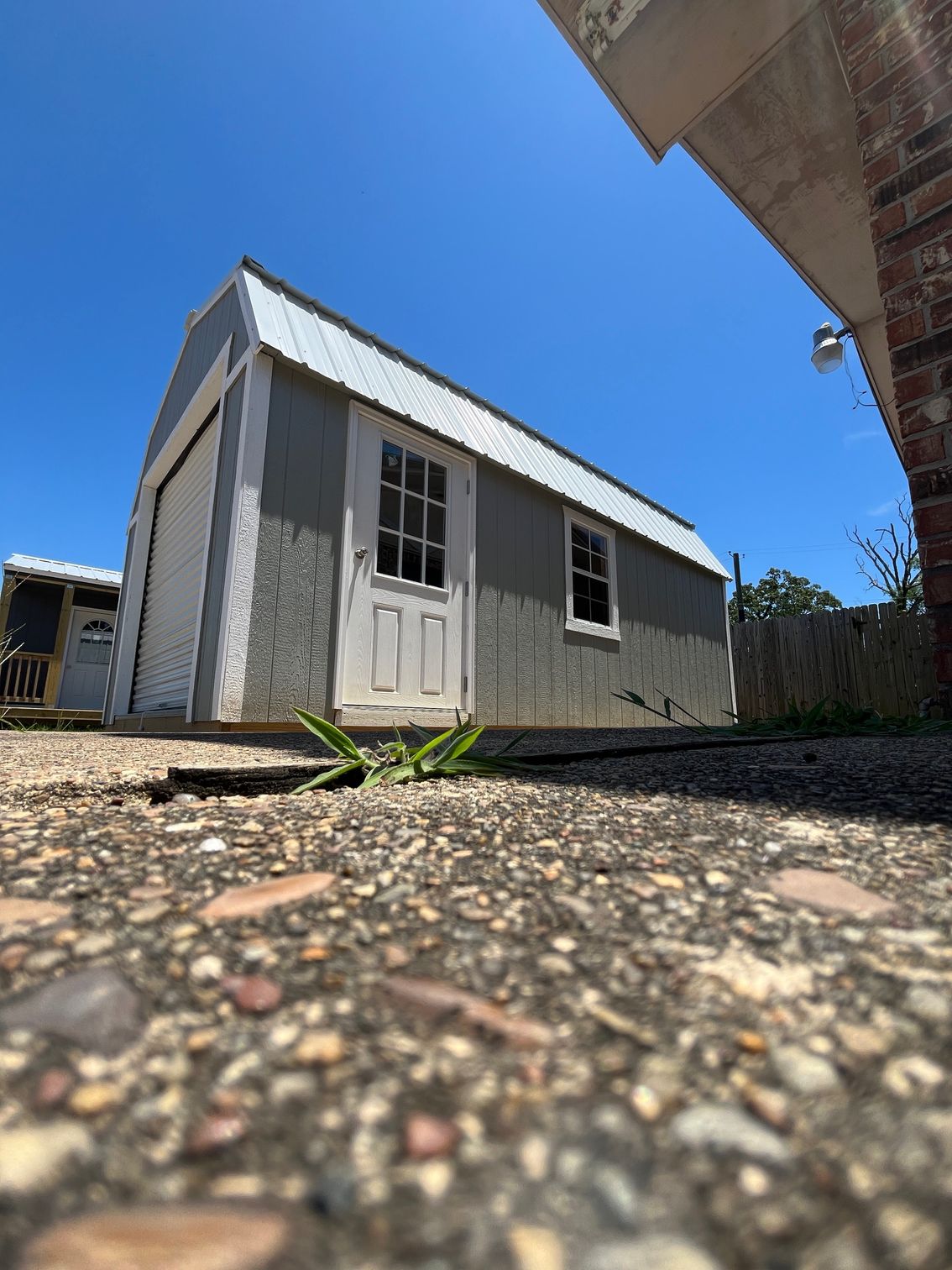A gray barn with a black roof and a door