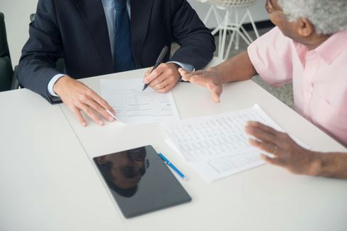 A man and a woman are sitting at a table looking at papers.