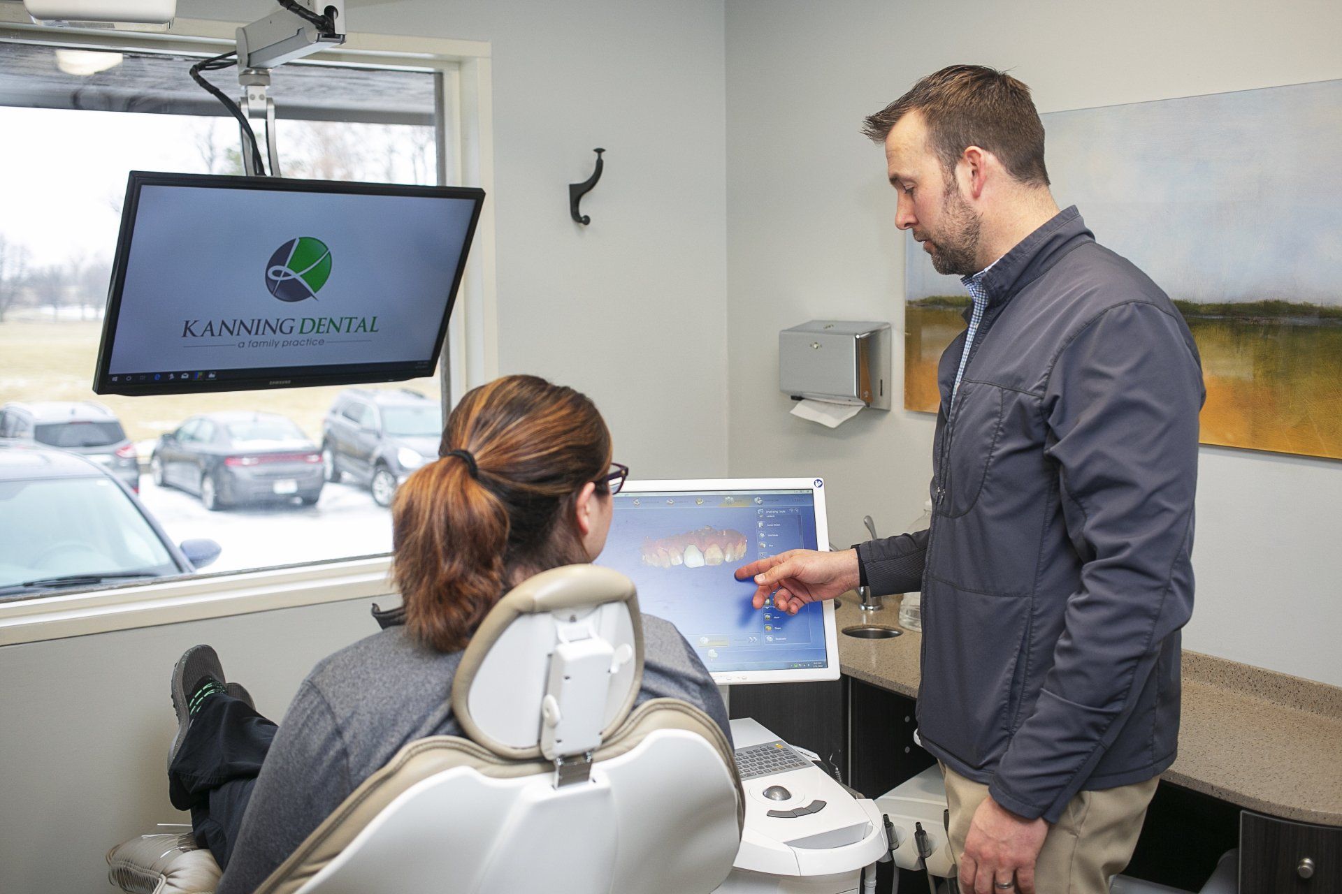 Visit the top dentist in Lawson, MO A man is talking to a woman in a dental chair.