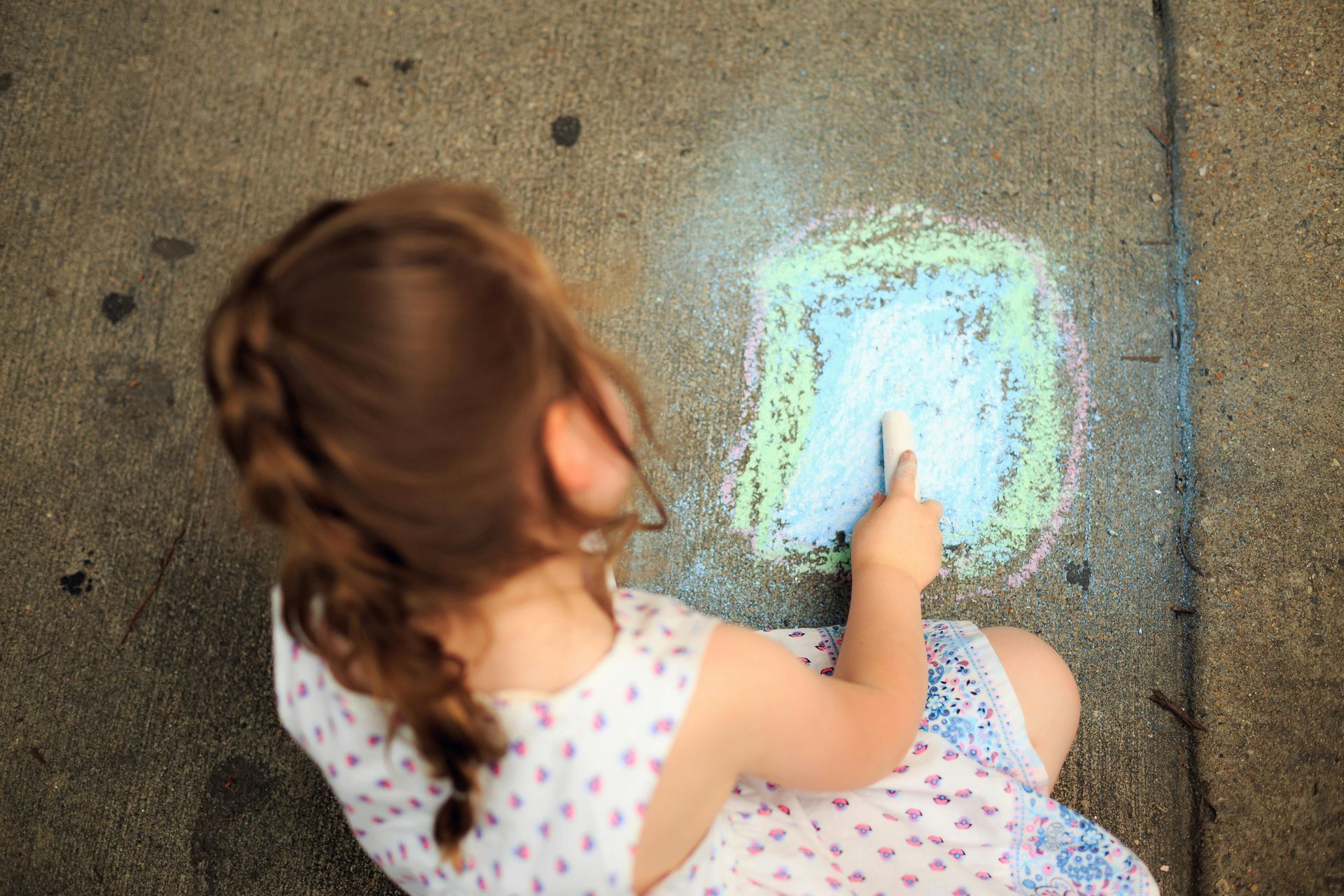 Child drawing with chalk on concrete.